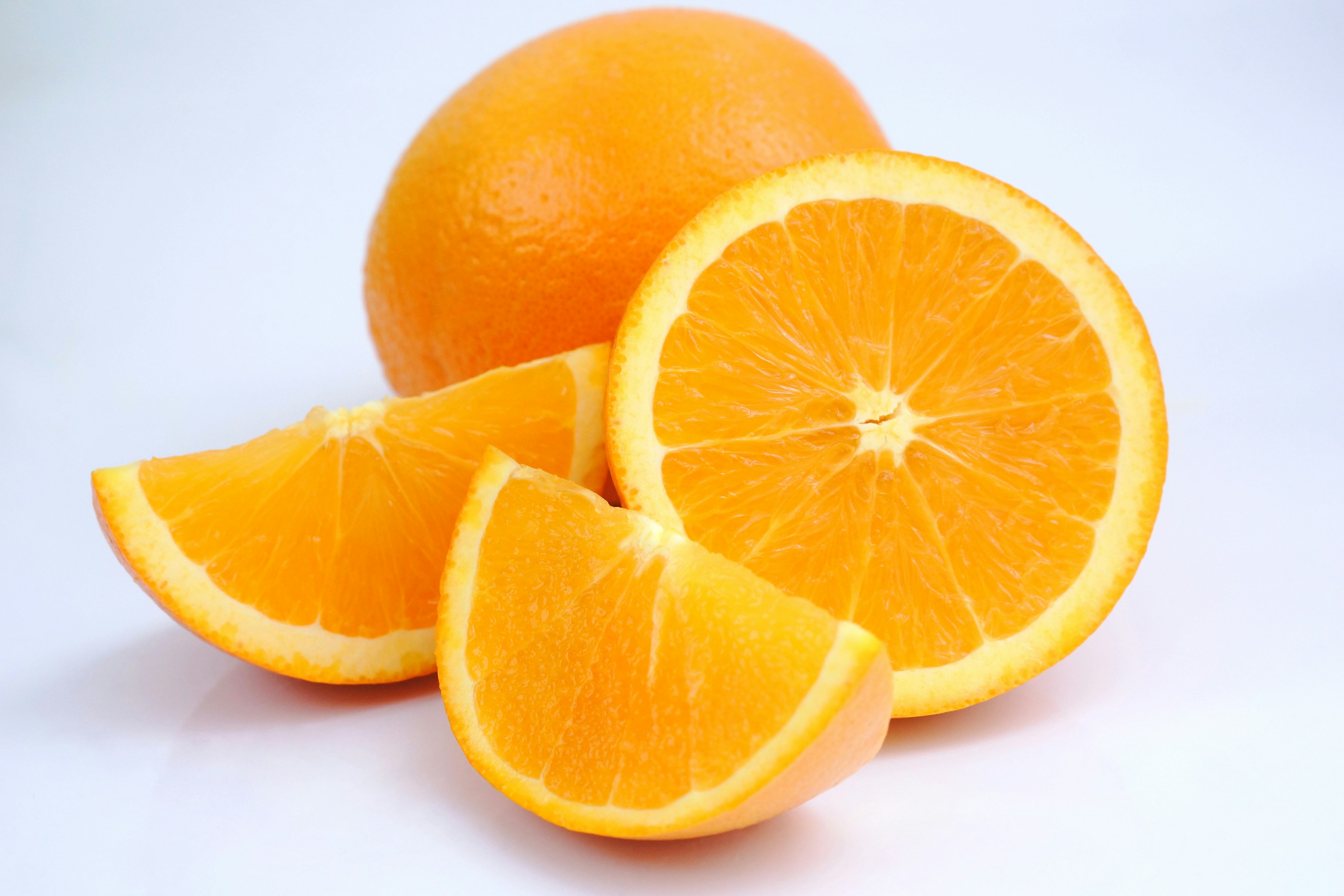 Whole orange and sliced oranges arranged on a white background