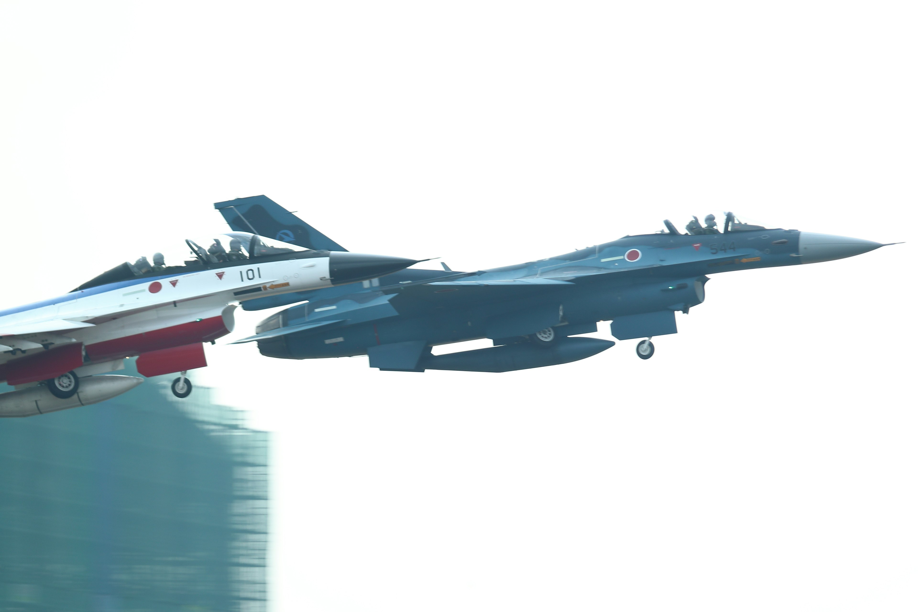 A blue fighter jet flying next to a red fighter jet