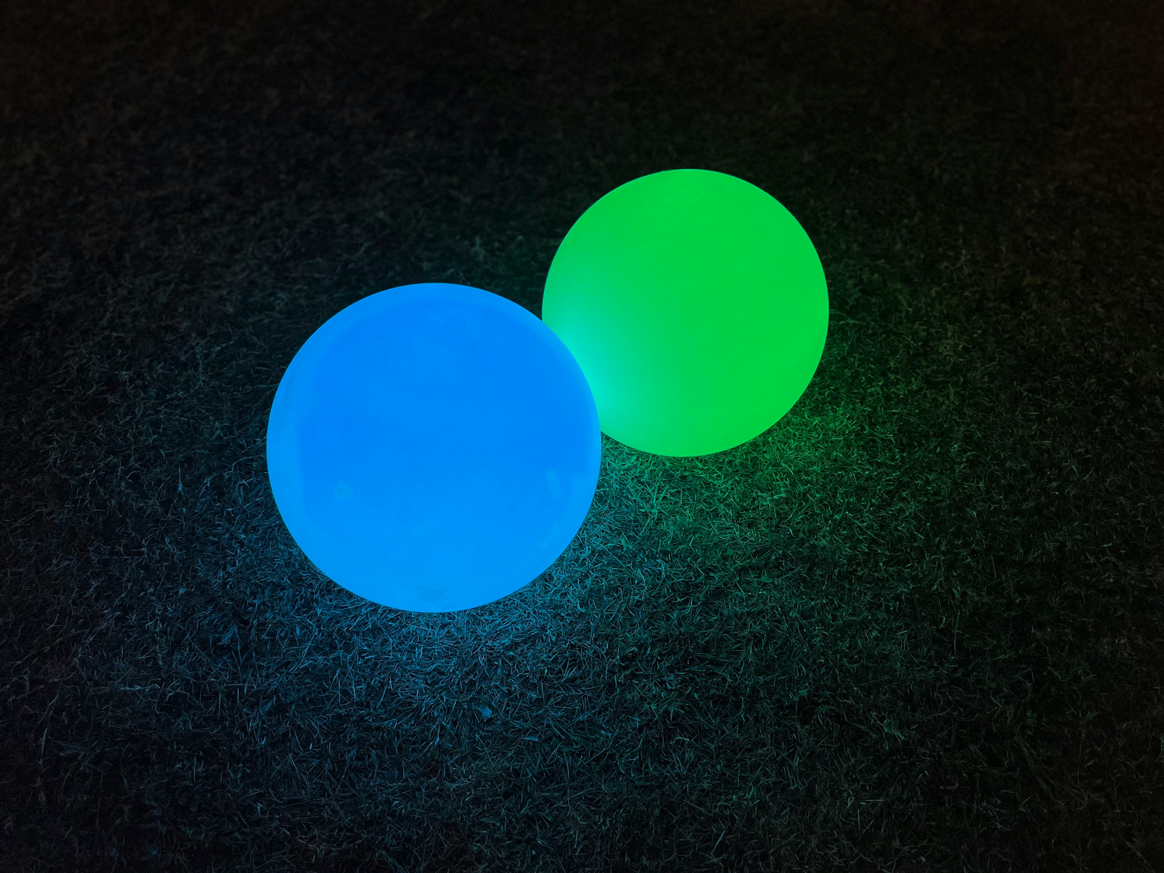 Two glowing spheres one blue and one green against a dark background