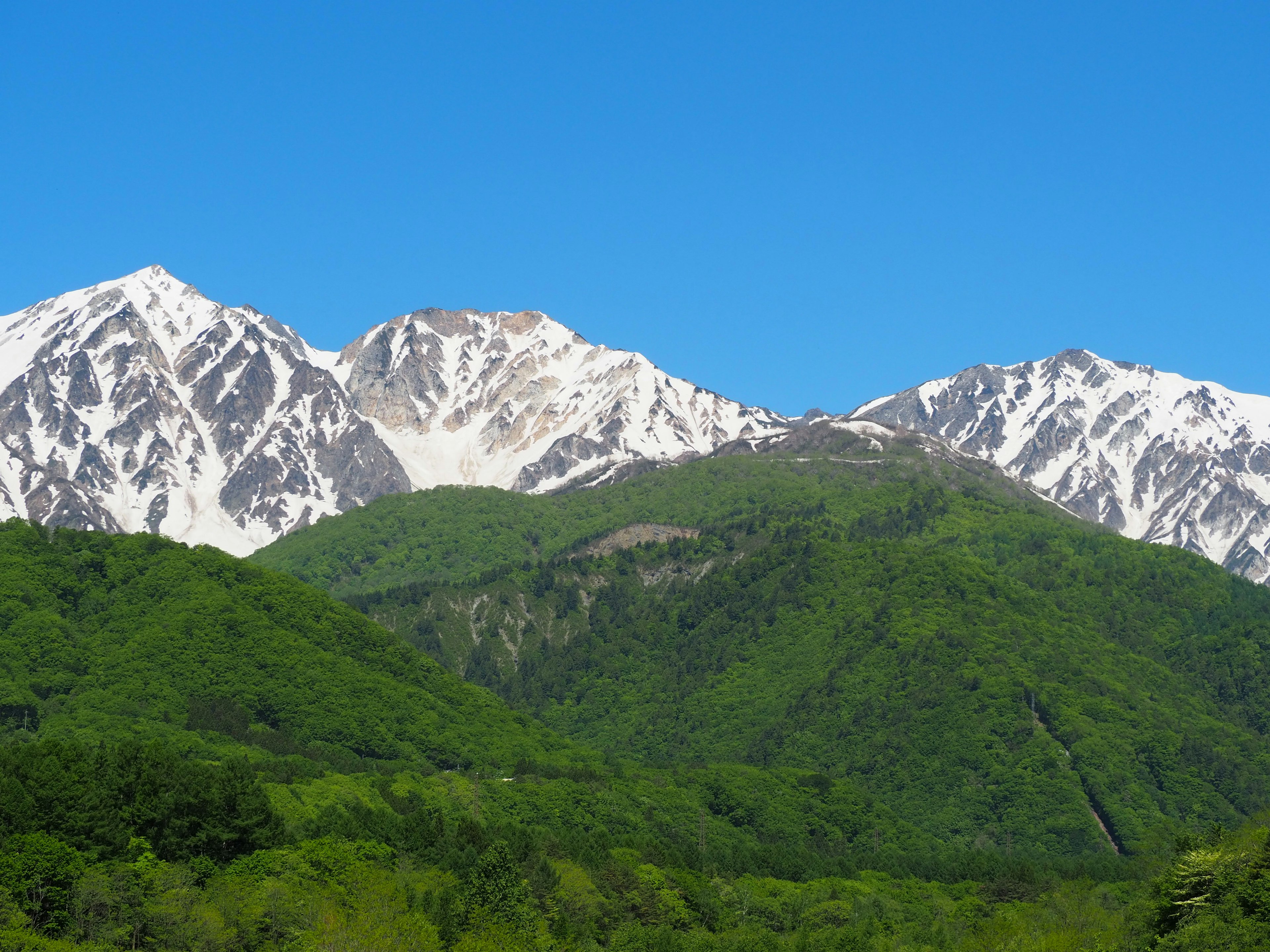 Scenic view of green mountains with snow-capped peaks