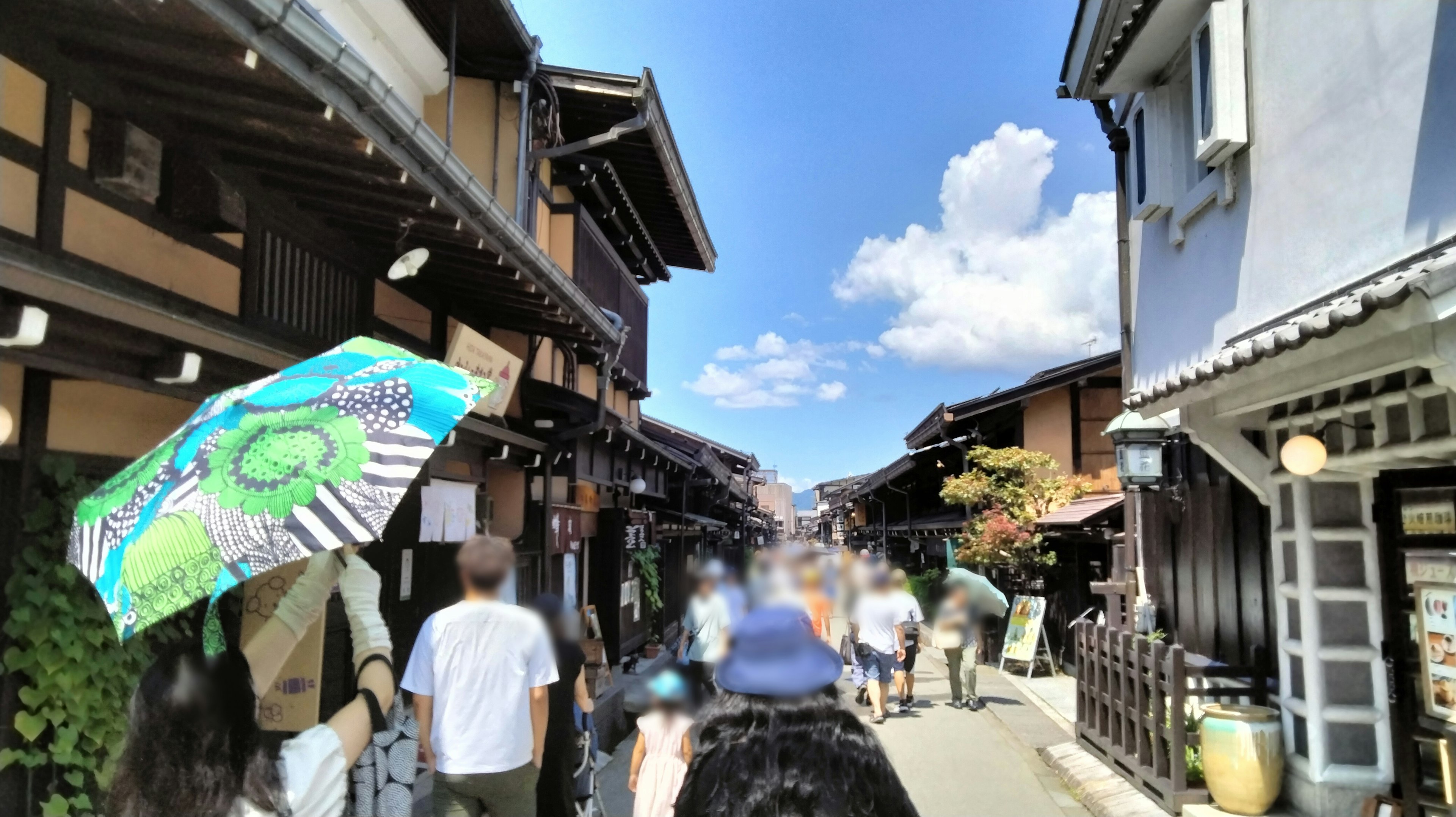 Belebte Straße in einer traditionellen japanischen Stadt mit blauem Himmel und weißen Wolken