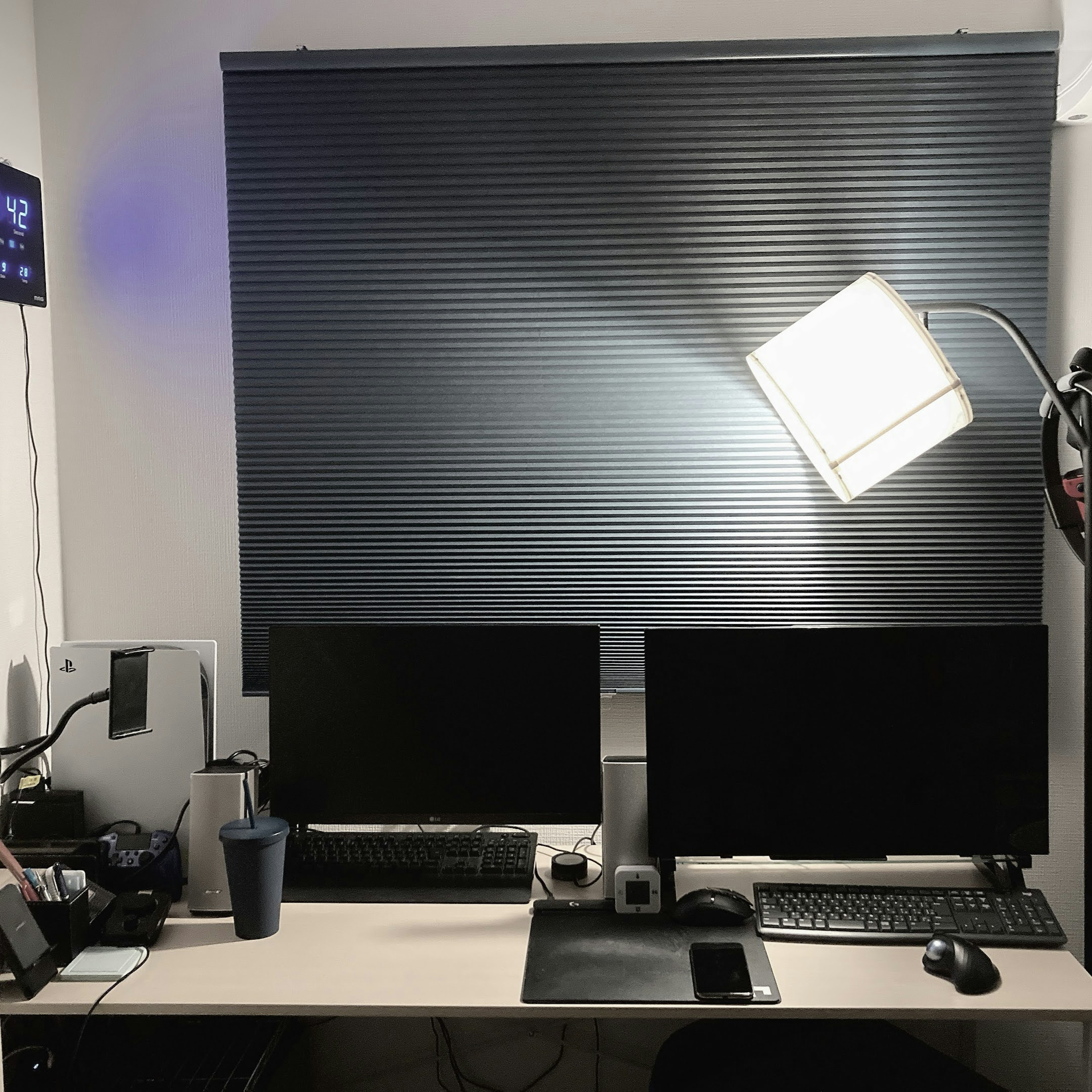 Simple desk with two monitors and a lamp in a workspace