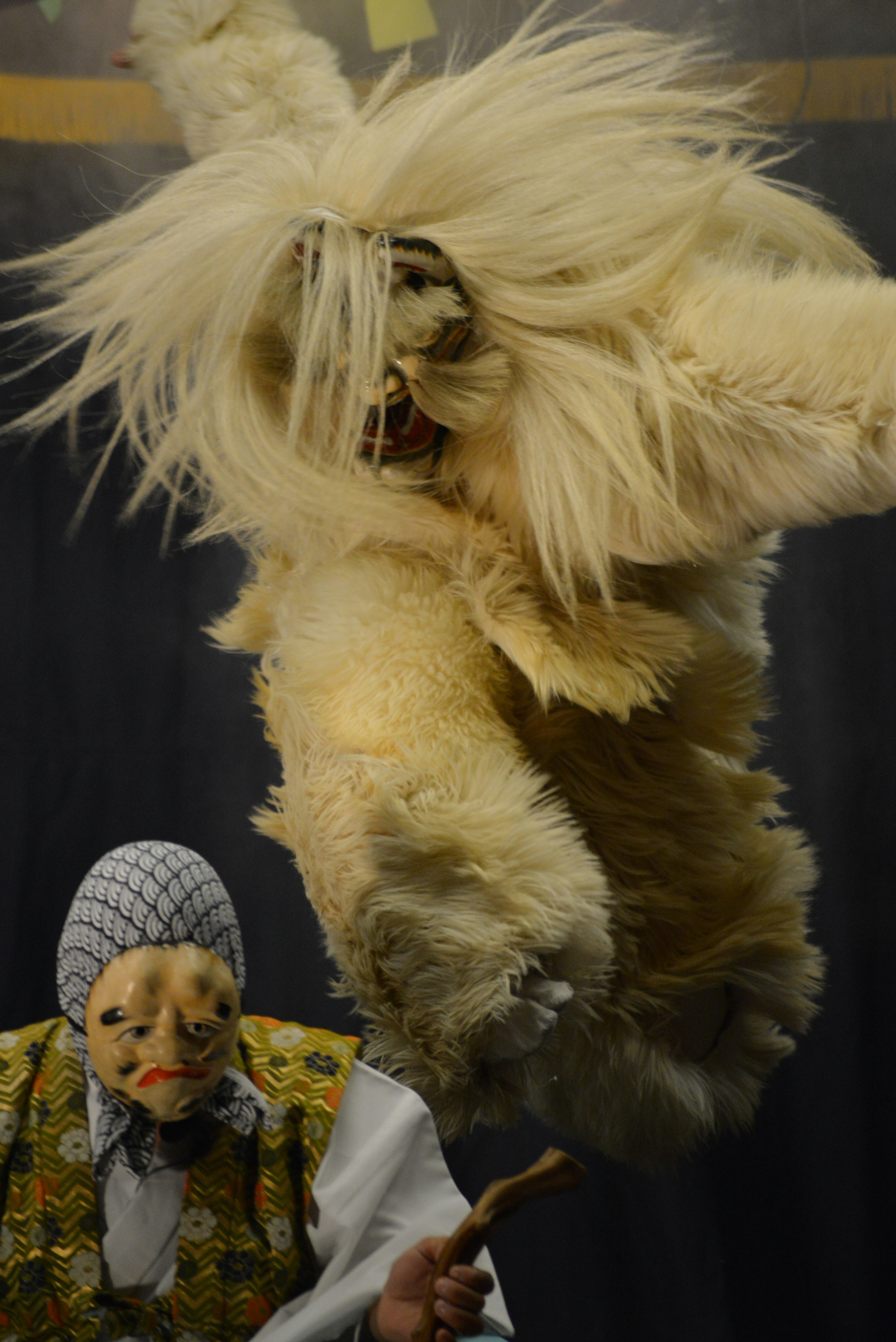 A fluffy white creature jumping with a puppet character in the foreground