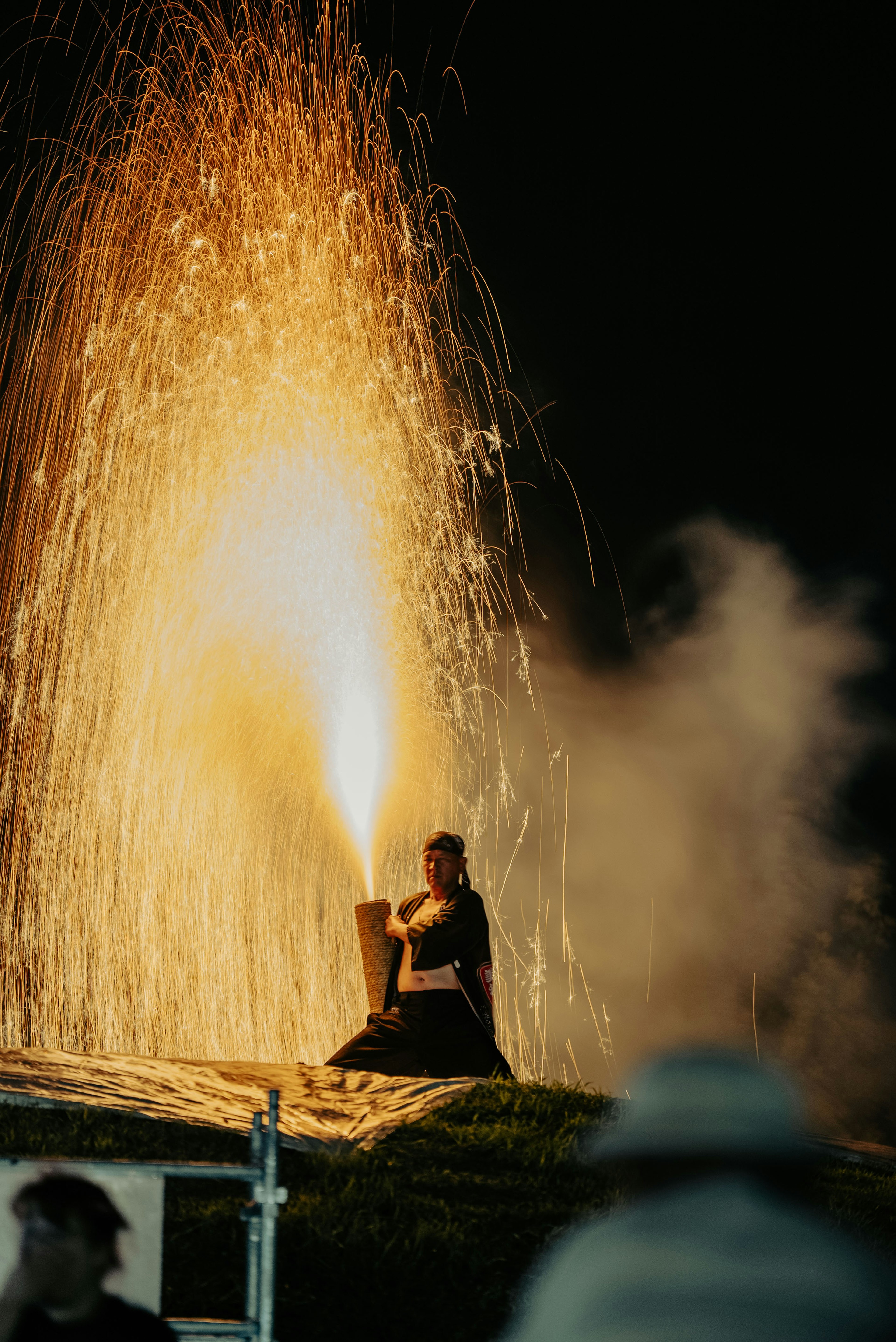 Person on a roof launching sparks during a nighttime festival