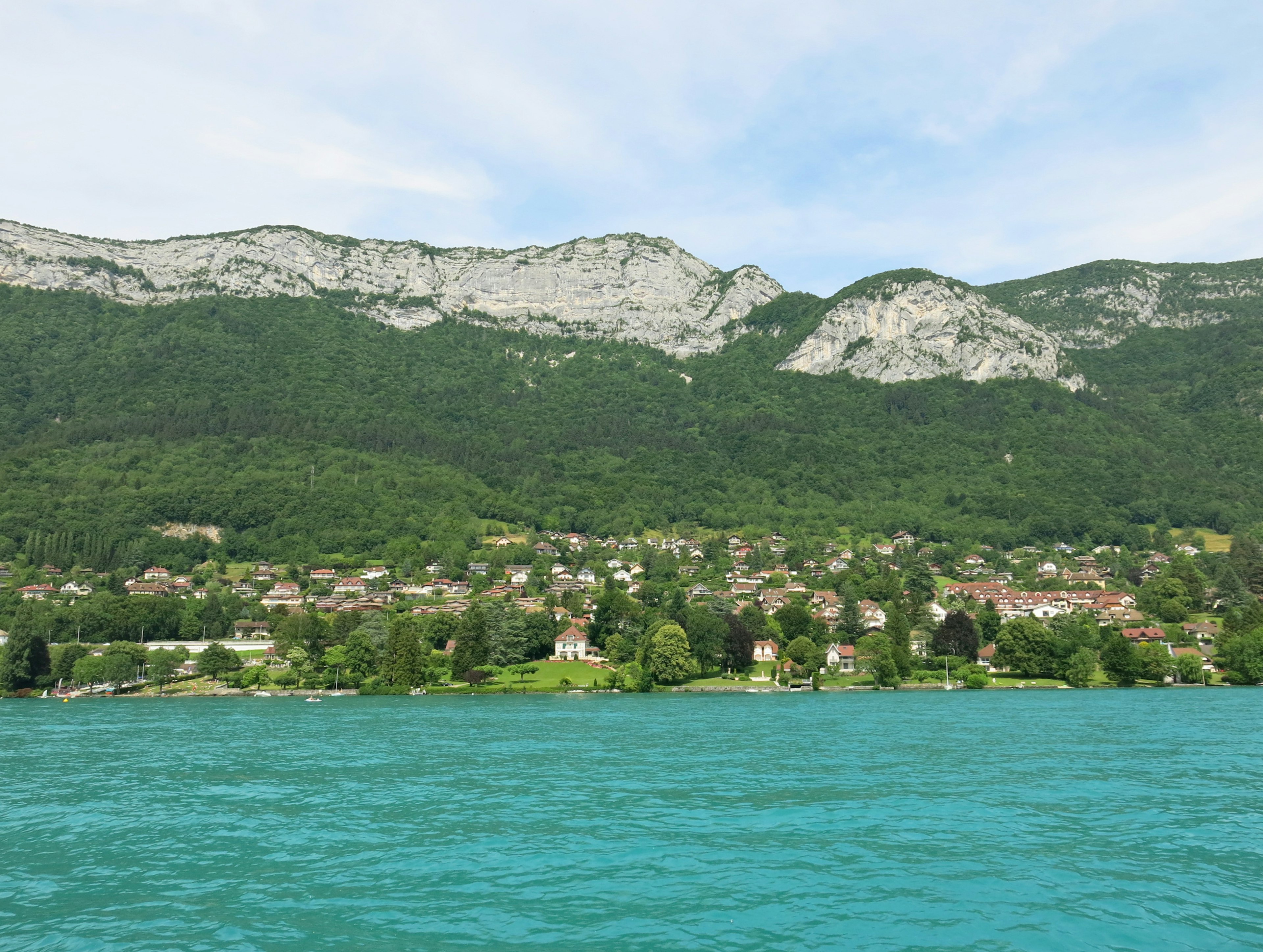 Vista escénica de un lago turquesa con montañas verdes y un pintoresco pueblo