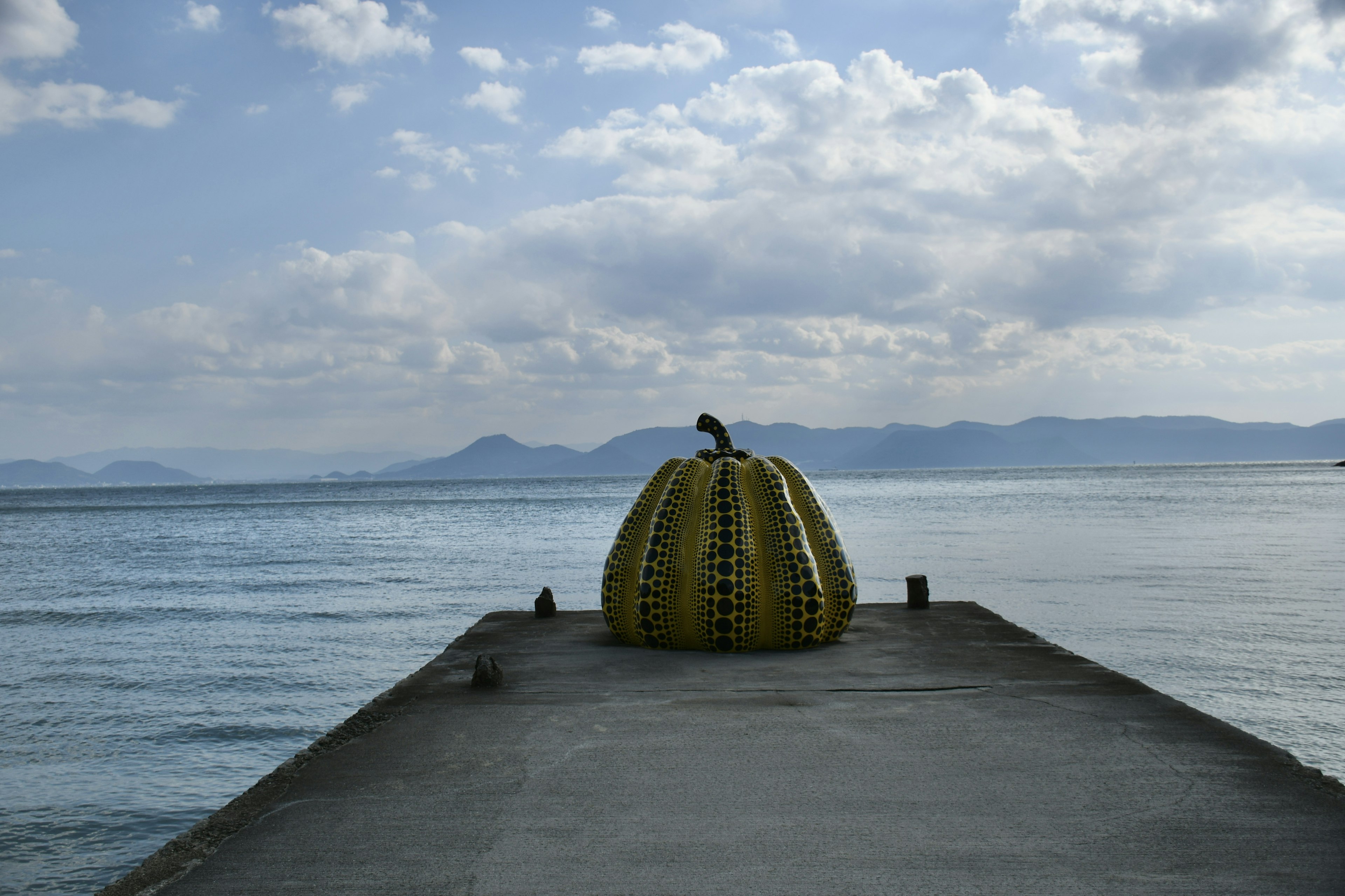 海に浮かぶ黄色いカボチャのオブジェがある桟橋の風景