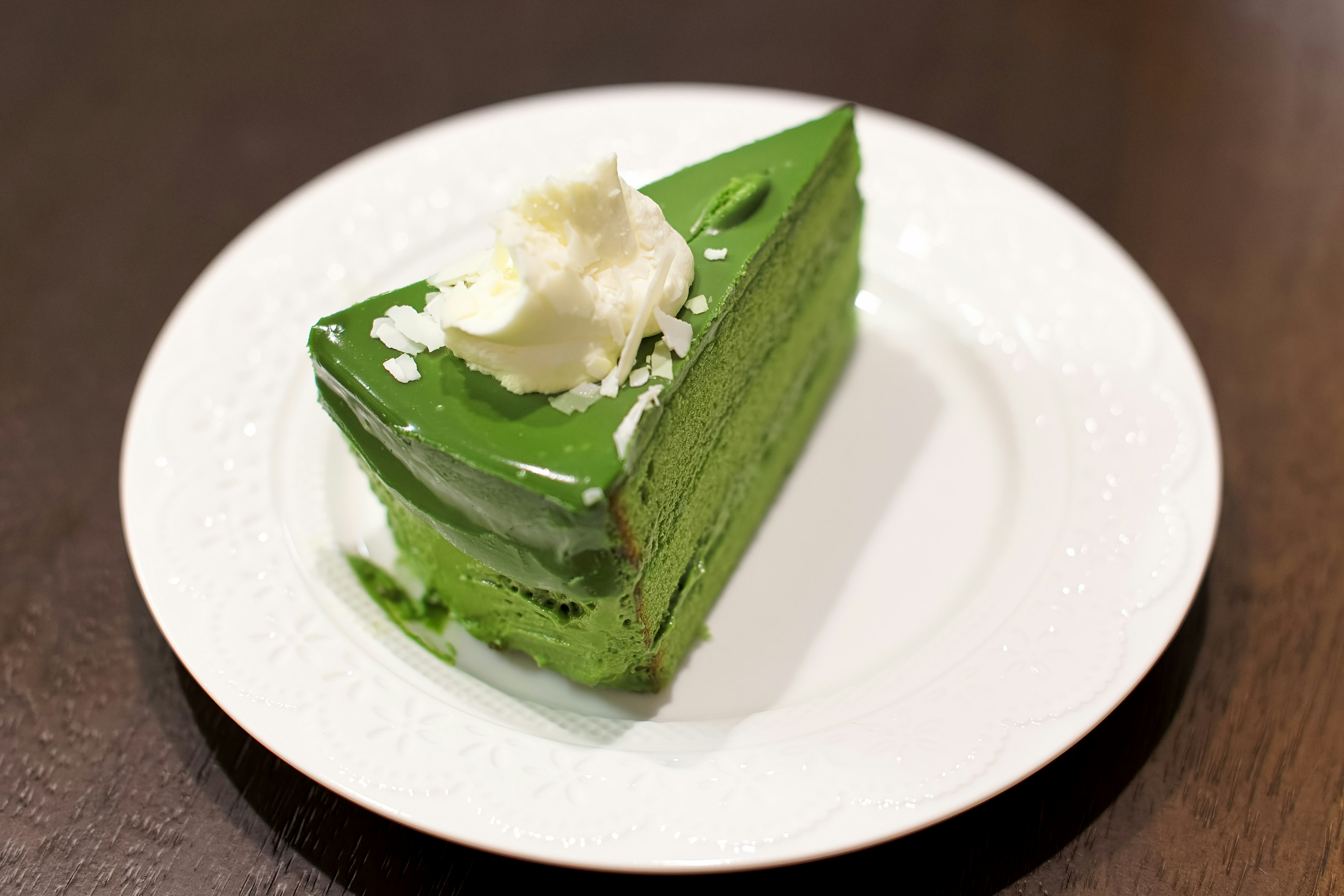 緑色の抹茶ケーキにホイップクリームのトッピング