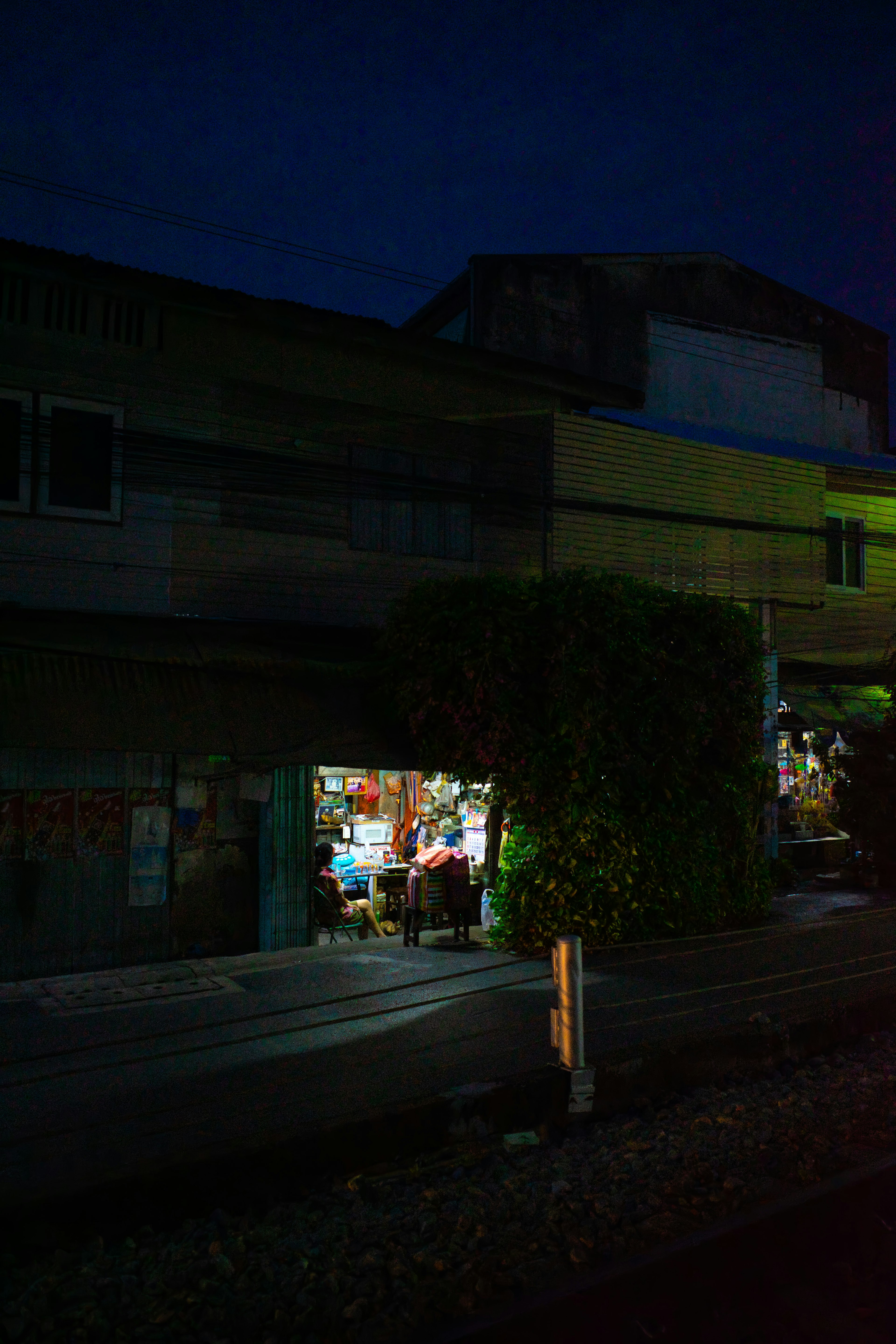 夜の街角にある小さな店舗の明かりが見える