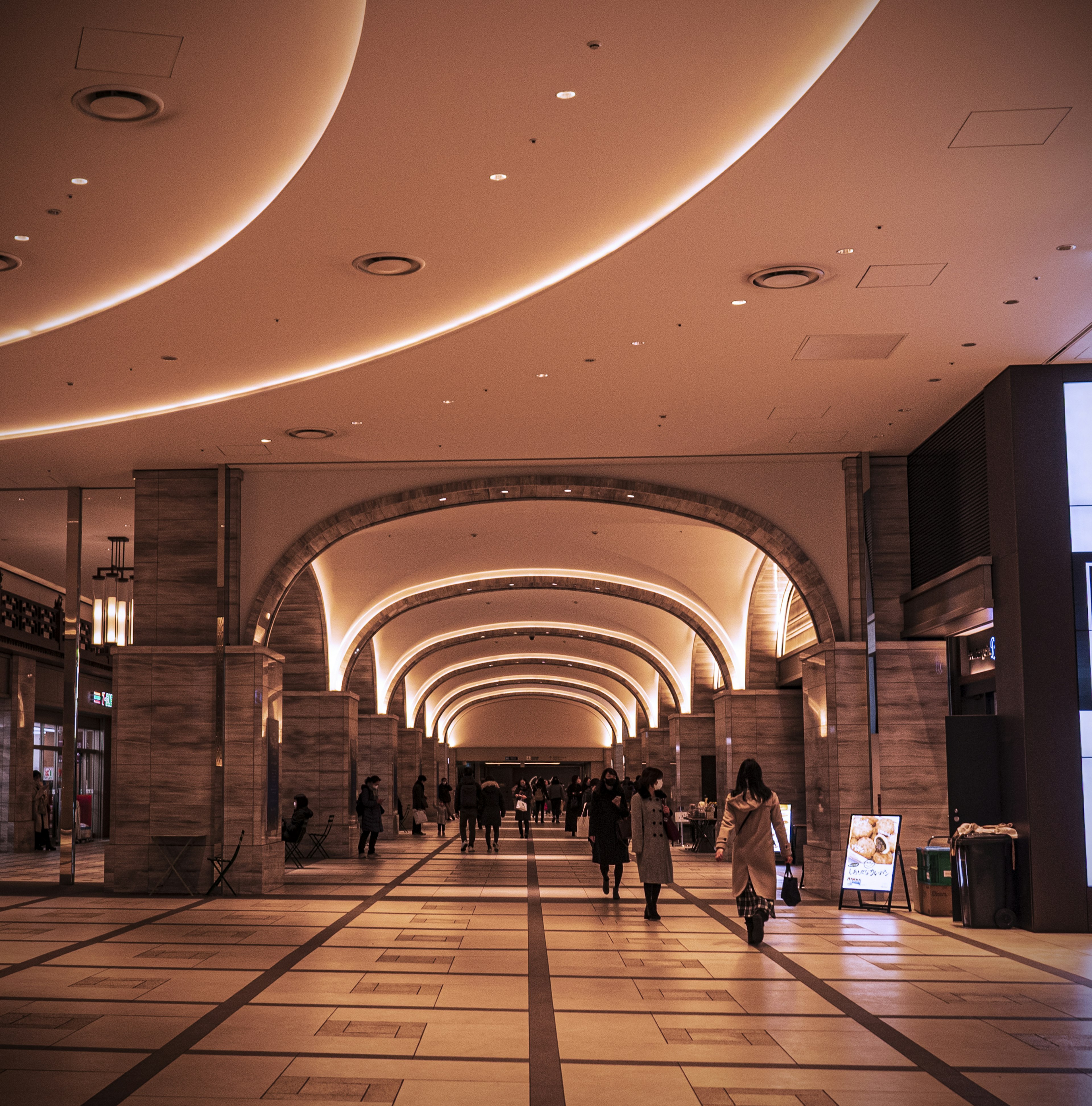 Arcade spaziosa con illuminazione brillante e persone che camminano