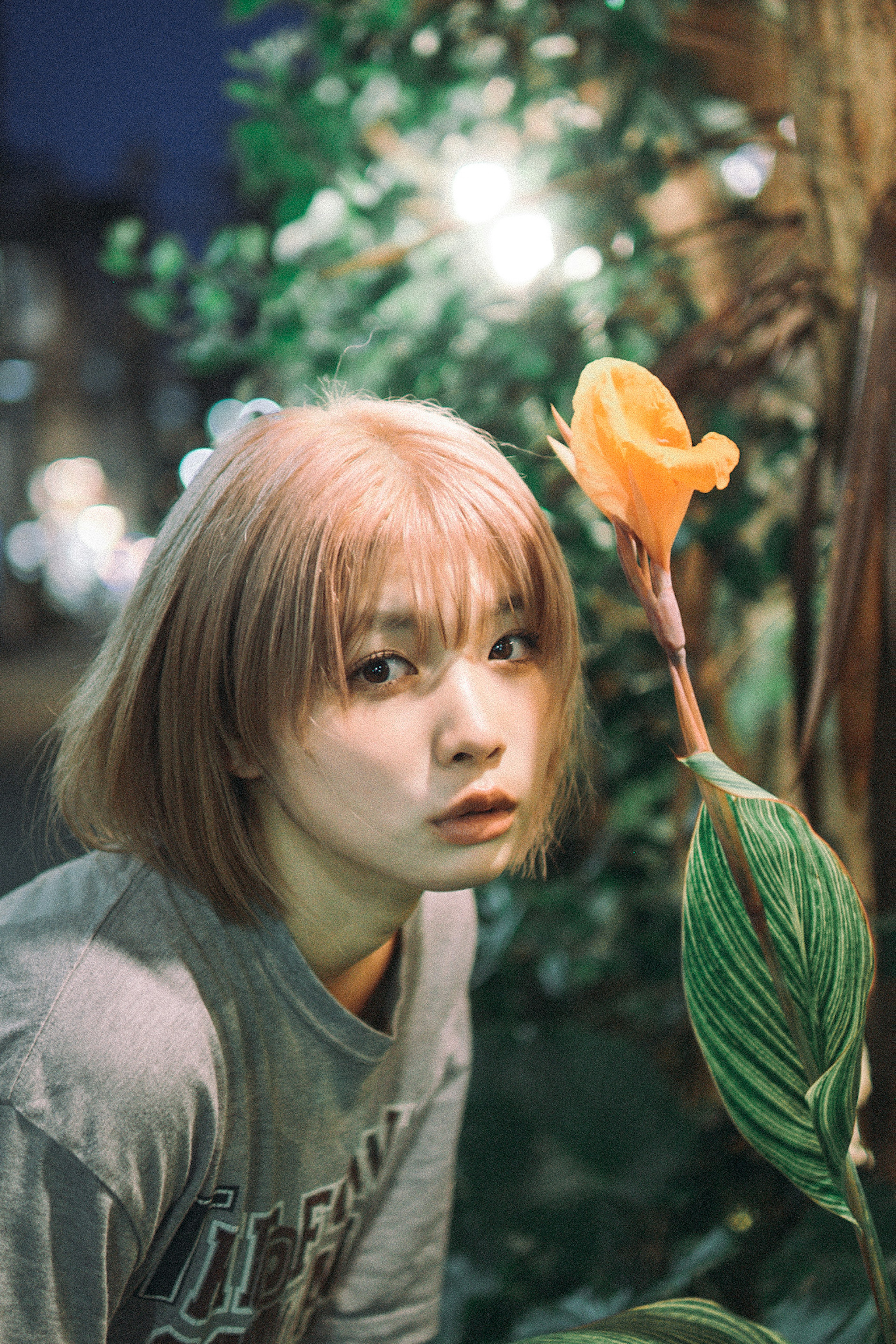 夜の背景に立つ短髪の少女とオレンジ色の花