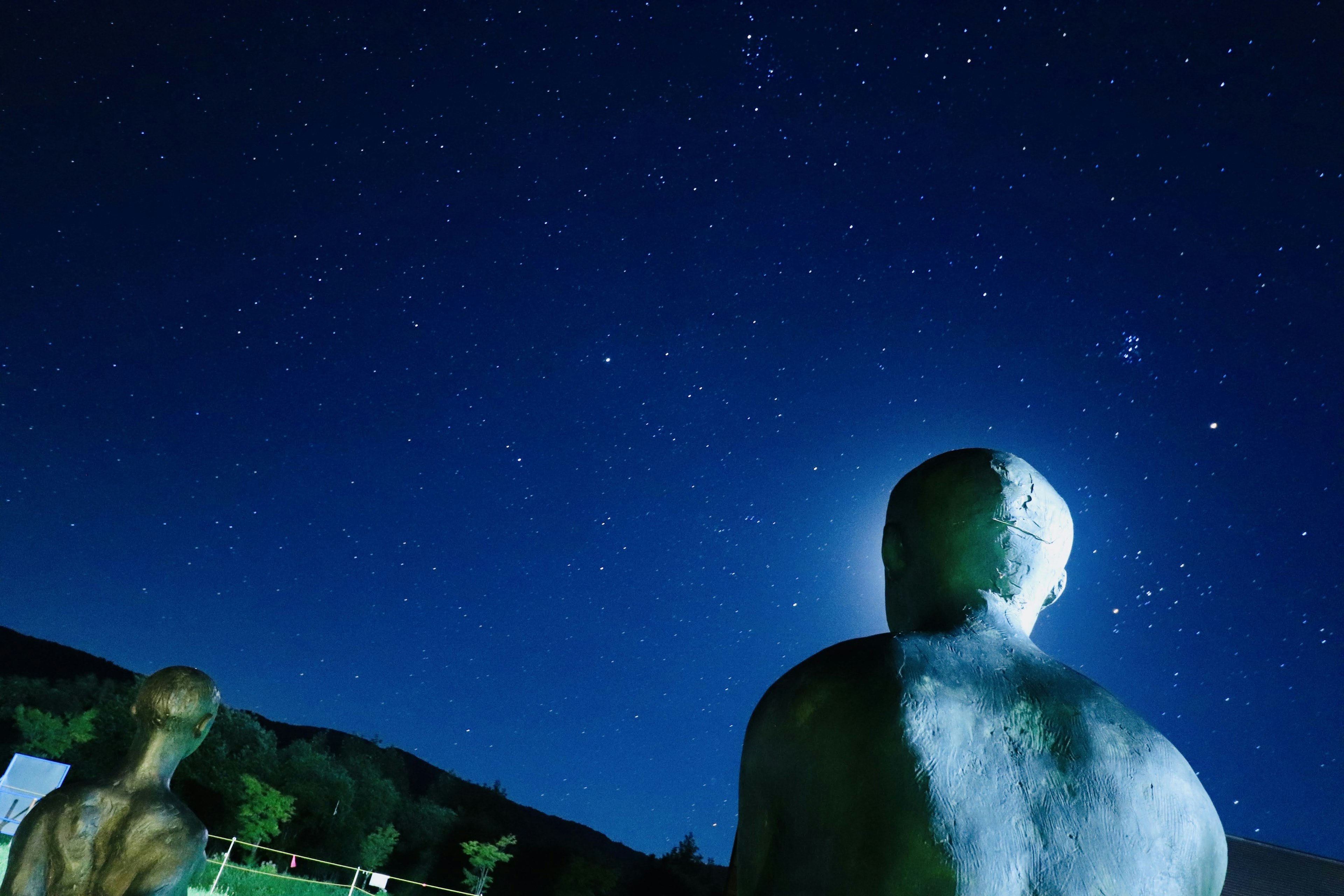 Esculturas humanas mirando un cielo estrellado