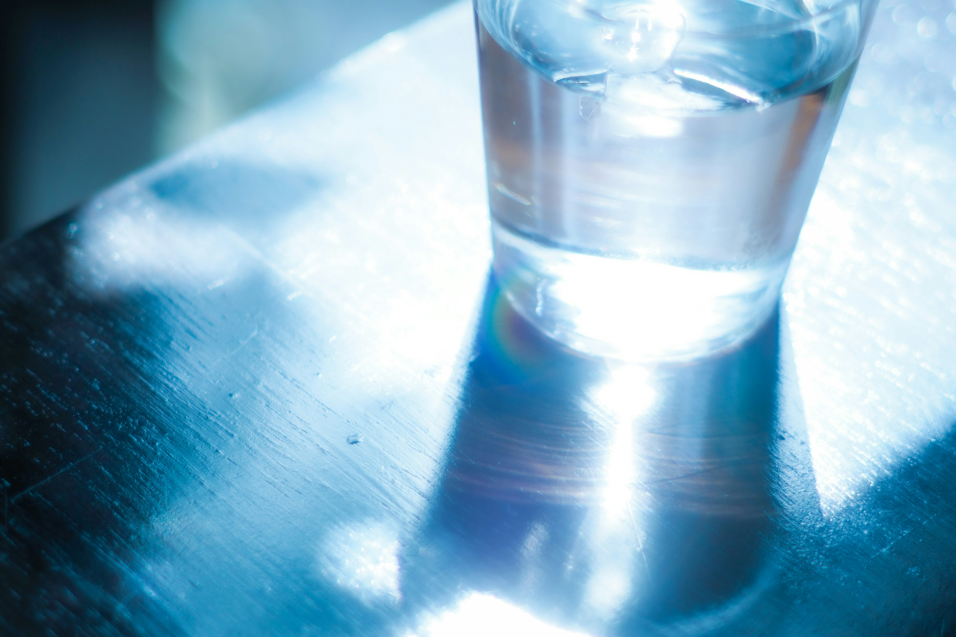 A clear glass of water reflecting blue light