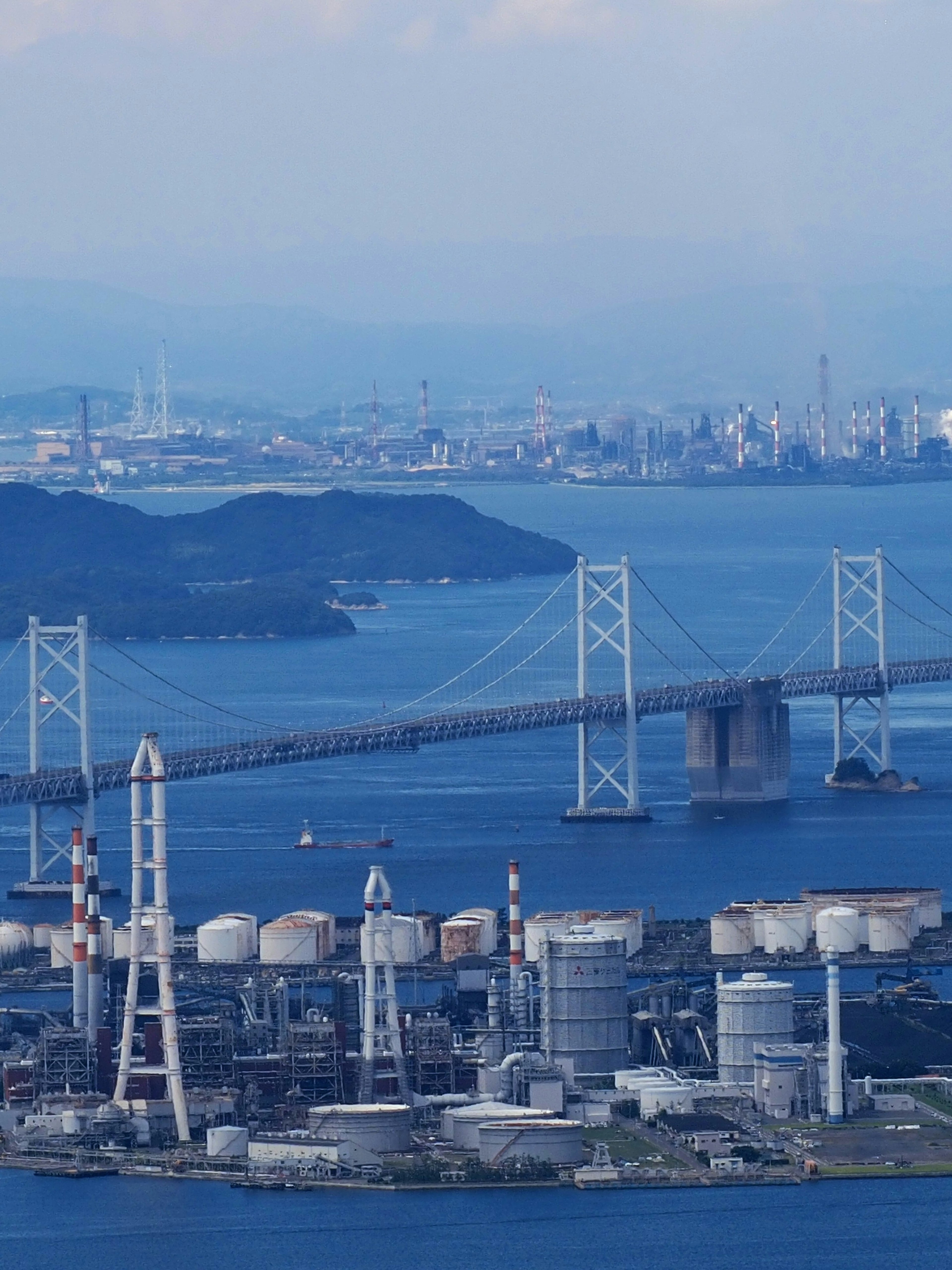 Una vista panoramica di acque blu e un ponte con un'area industriale e uno sfondo urbano