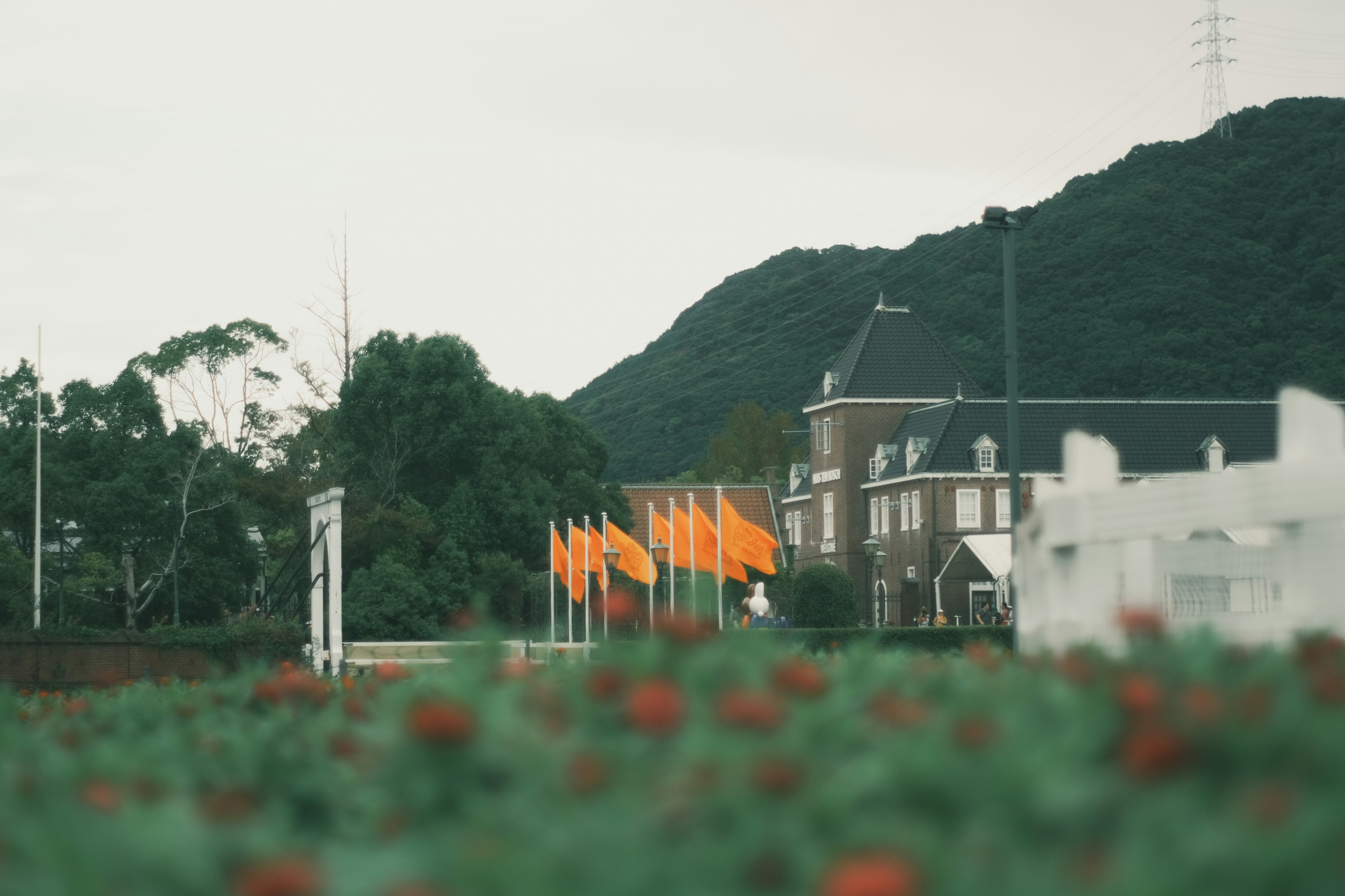 Paysage avec des drapeaux orange et un bâtiment blanc avec une montagne verte en arrière-plan