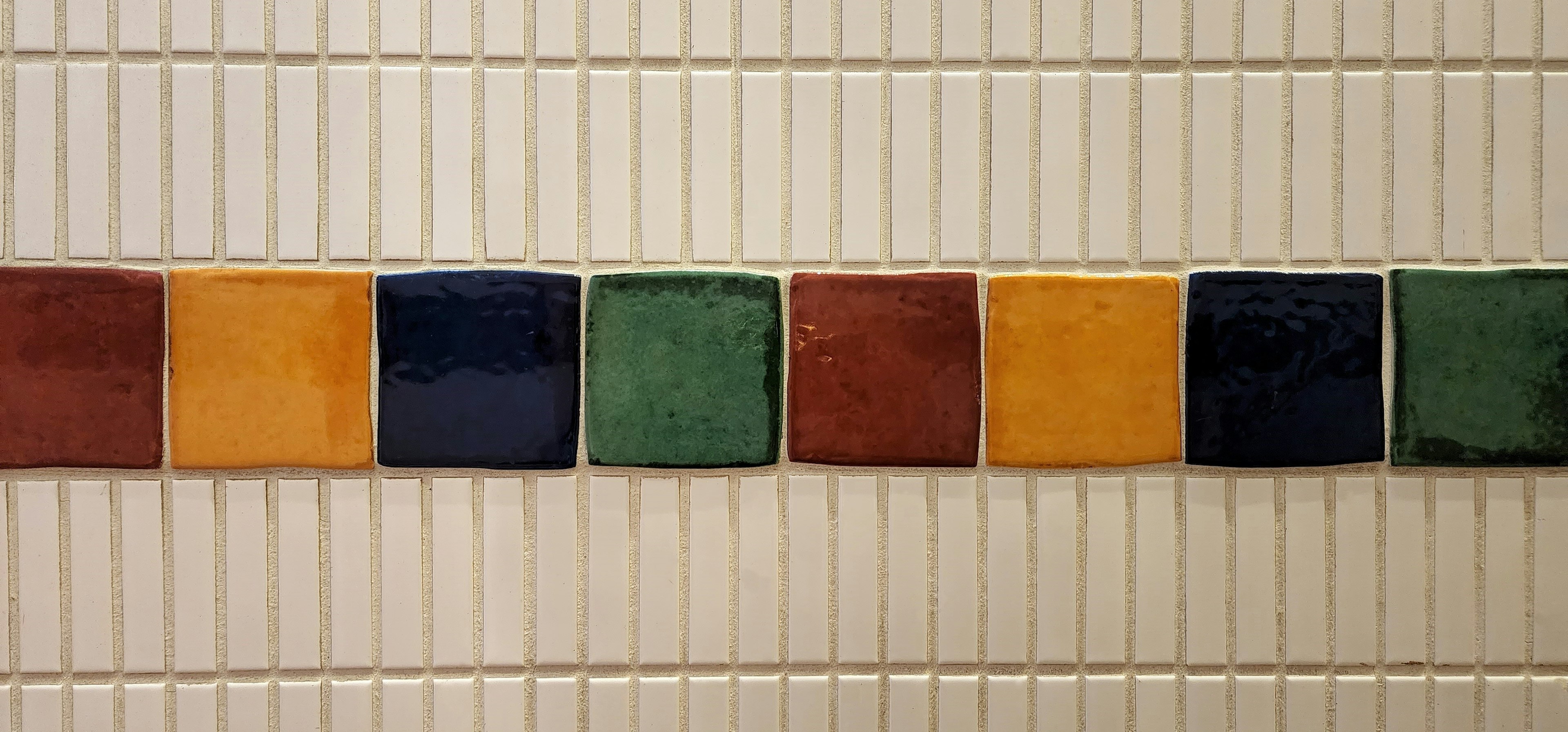 Colorful tiles arranged in a horizontal line on a wall