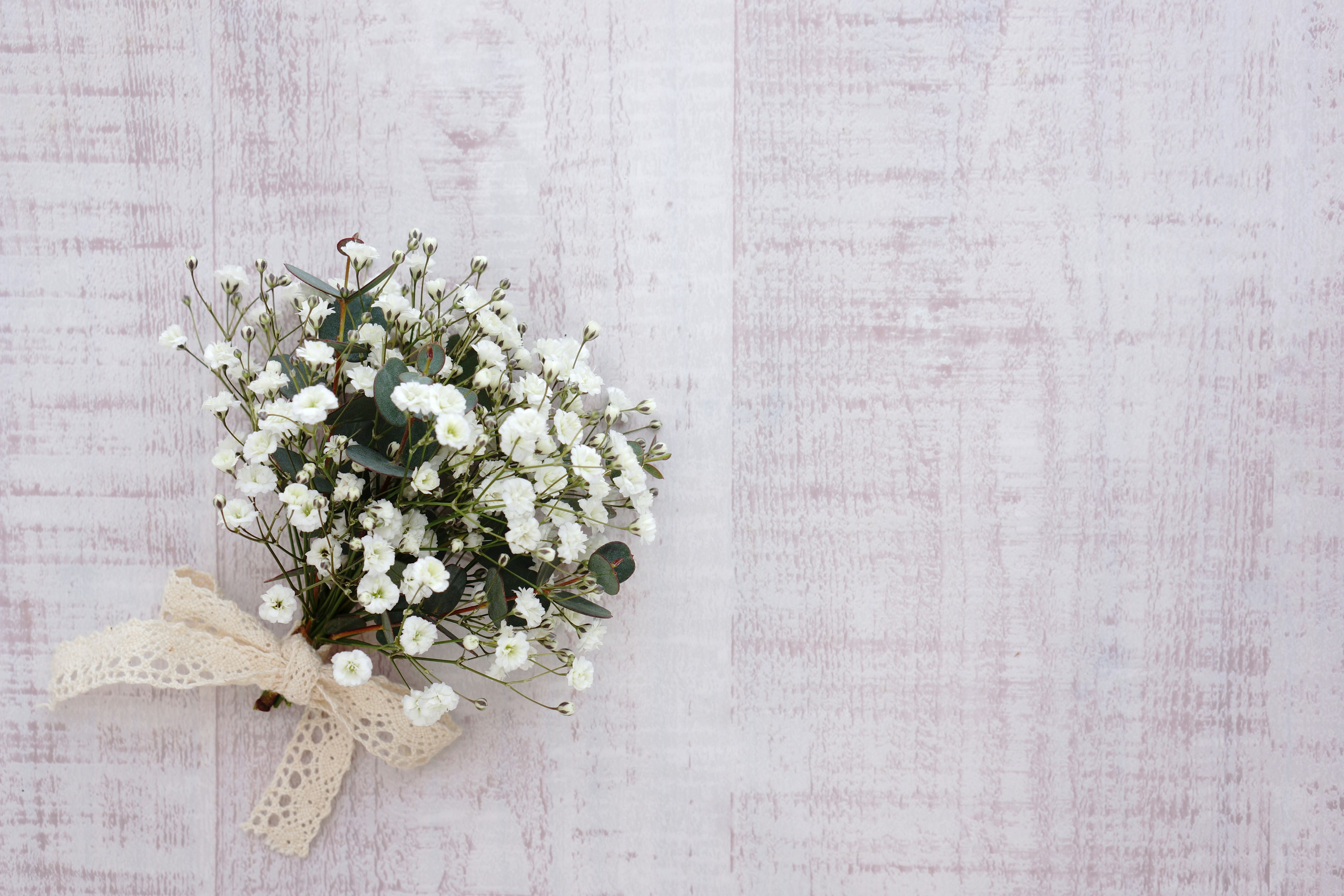 Un ramo de flores blancas atado con una cinta sobre un fondo de madera clara