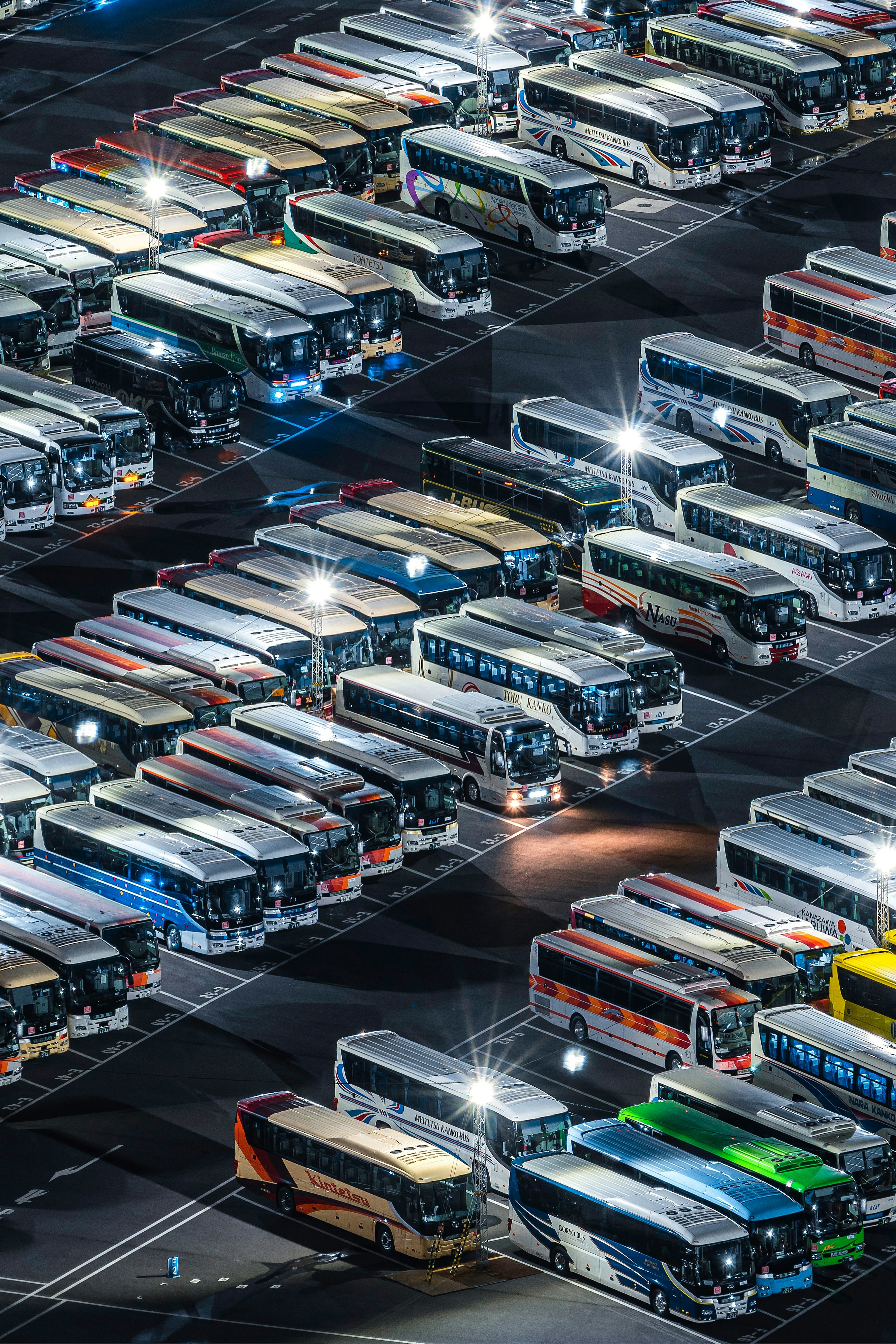 Vista aérea de numerosos autobuses estacionados en un depósito de autobuses bien iluminado