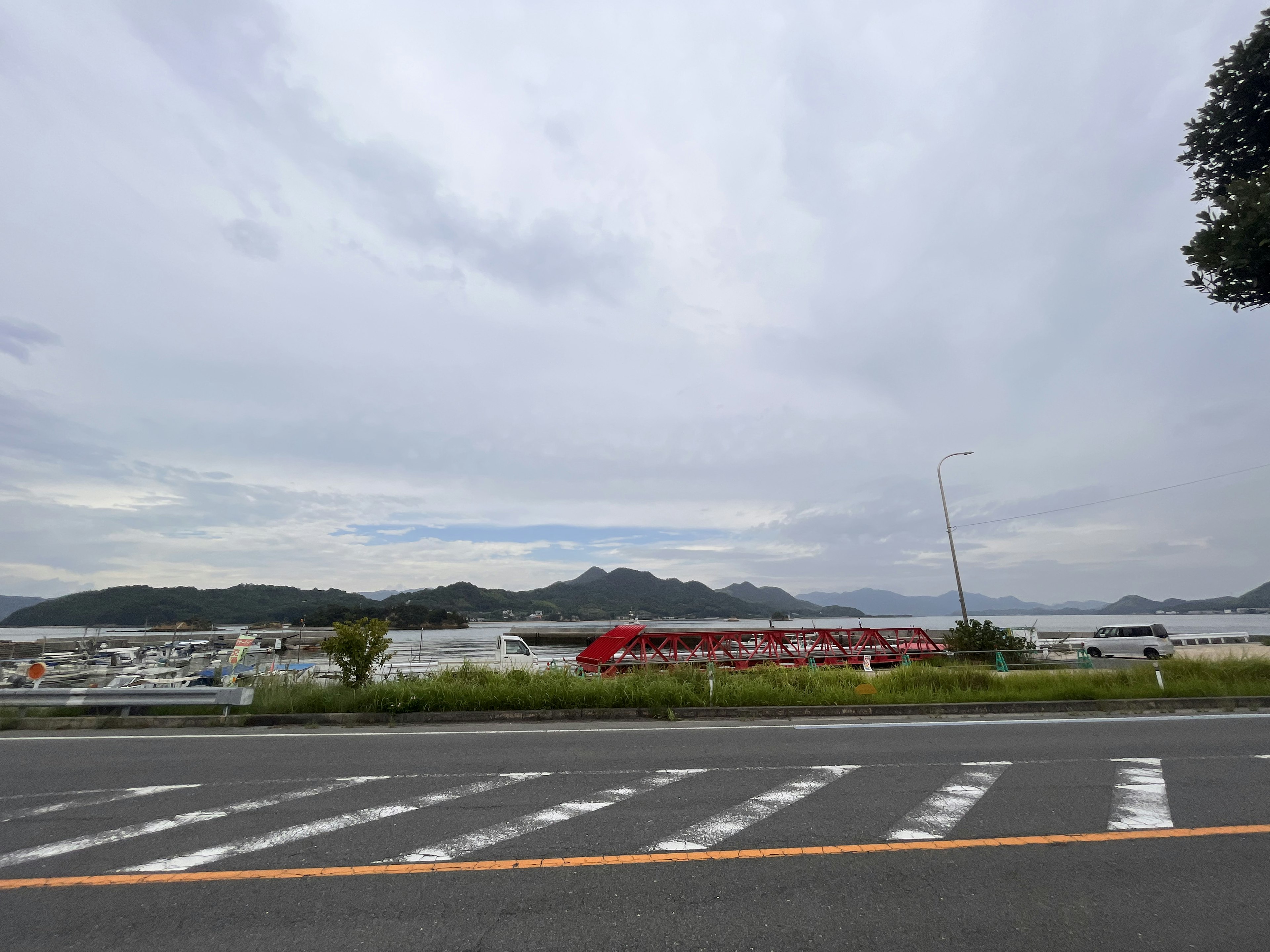 青い空の下に広がる海と山の風景 道路と白い横断歩道が見える