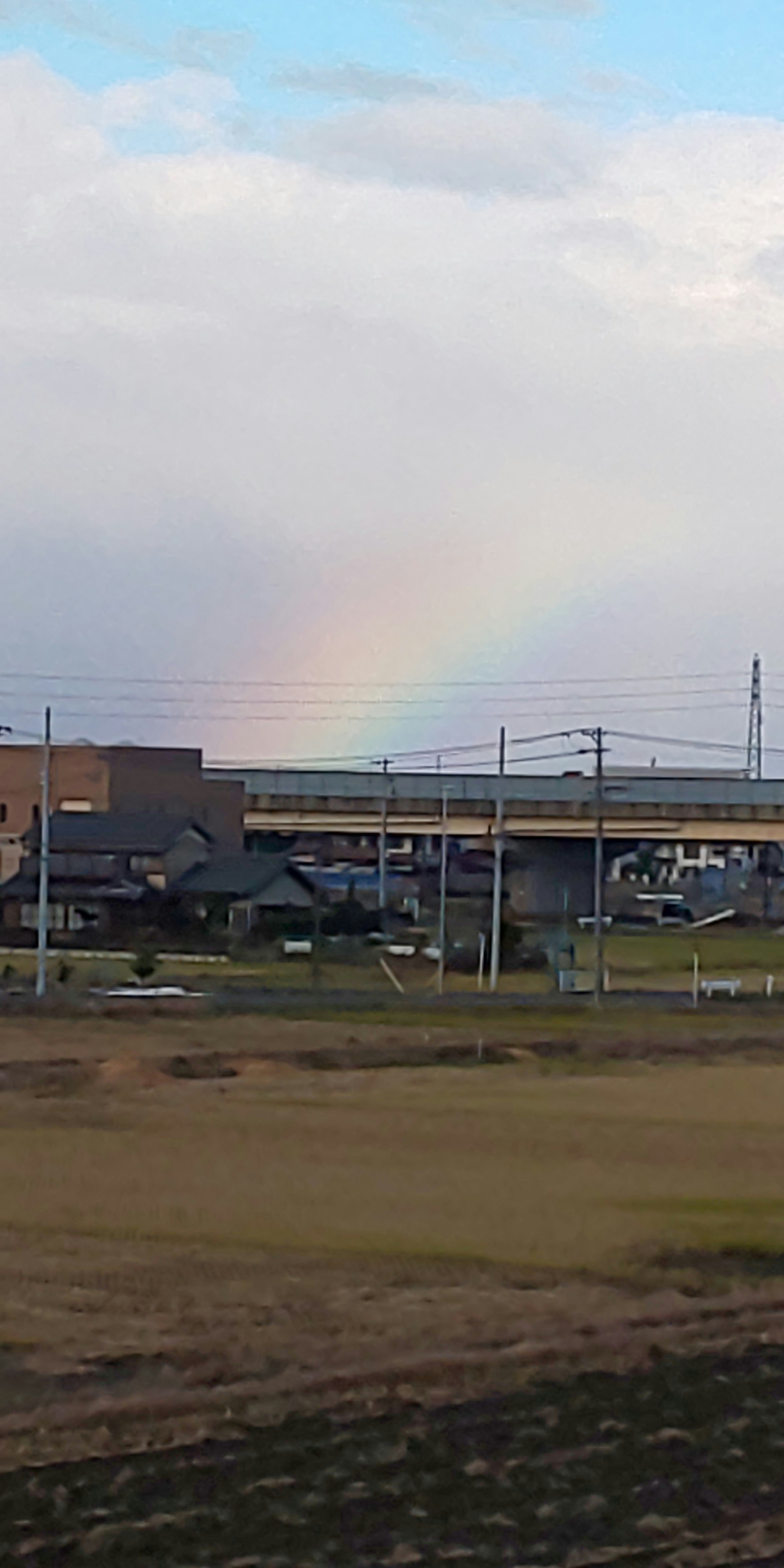 Un paesaggio con un arcobaleno contro un cielo blu e nuvole