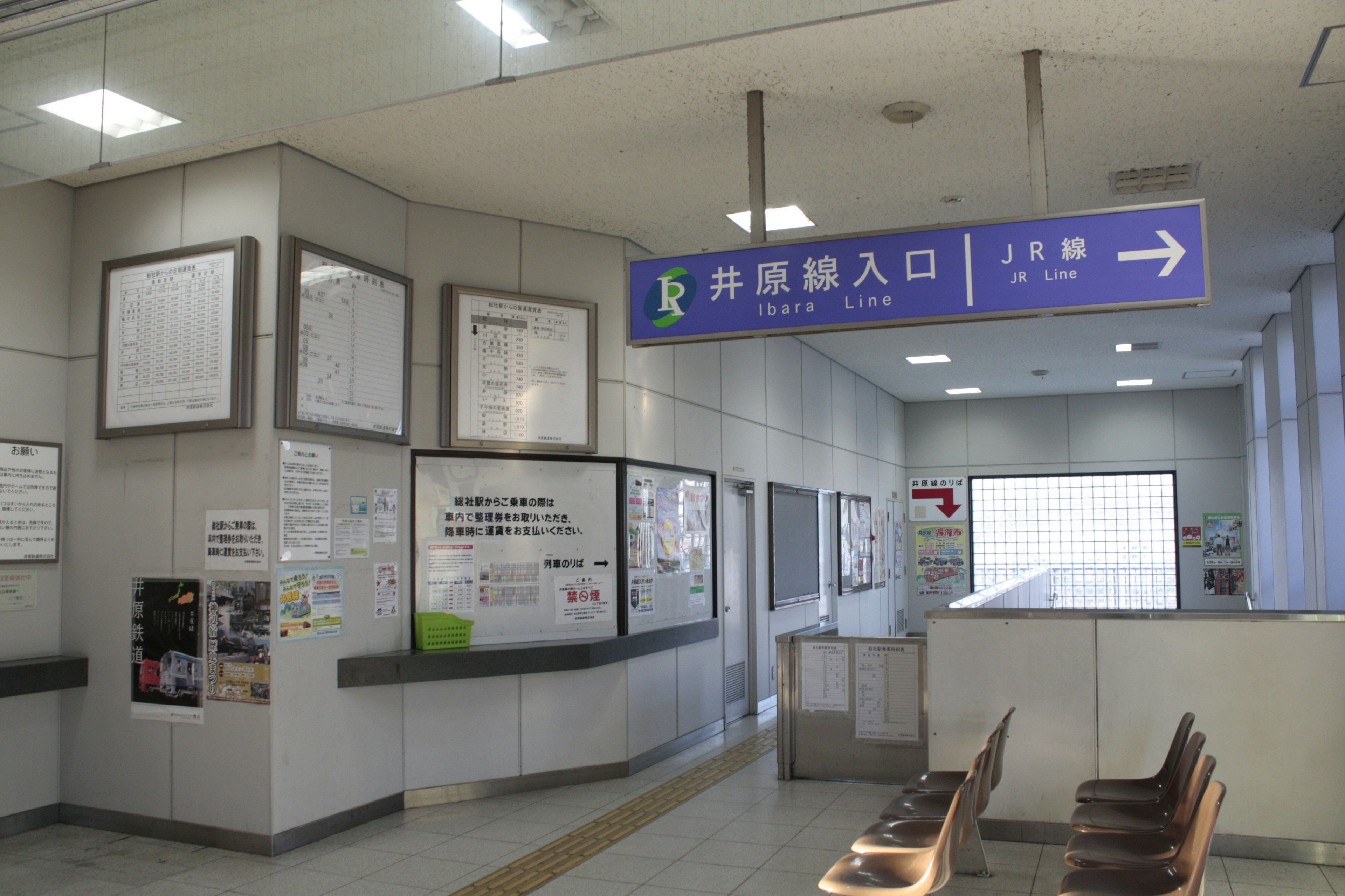 Interior of a train station with a blue entrance sign and waiting area chairs