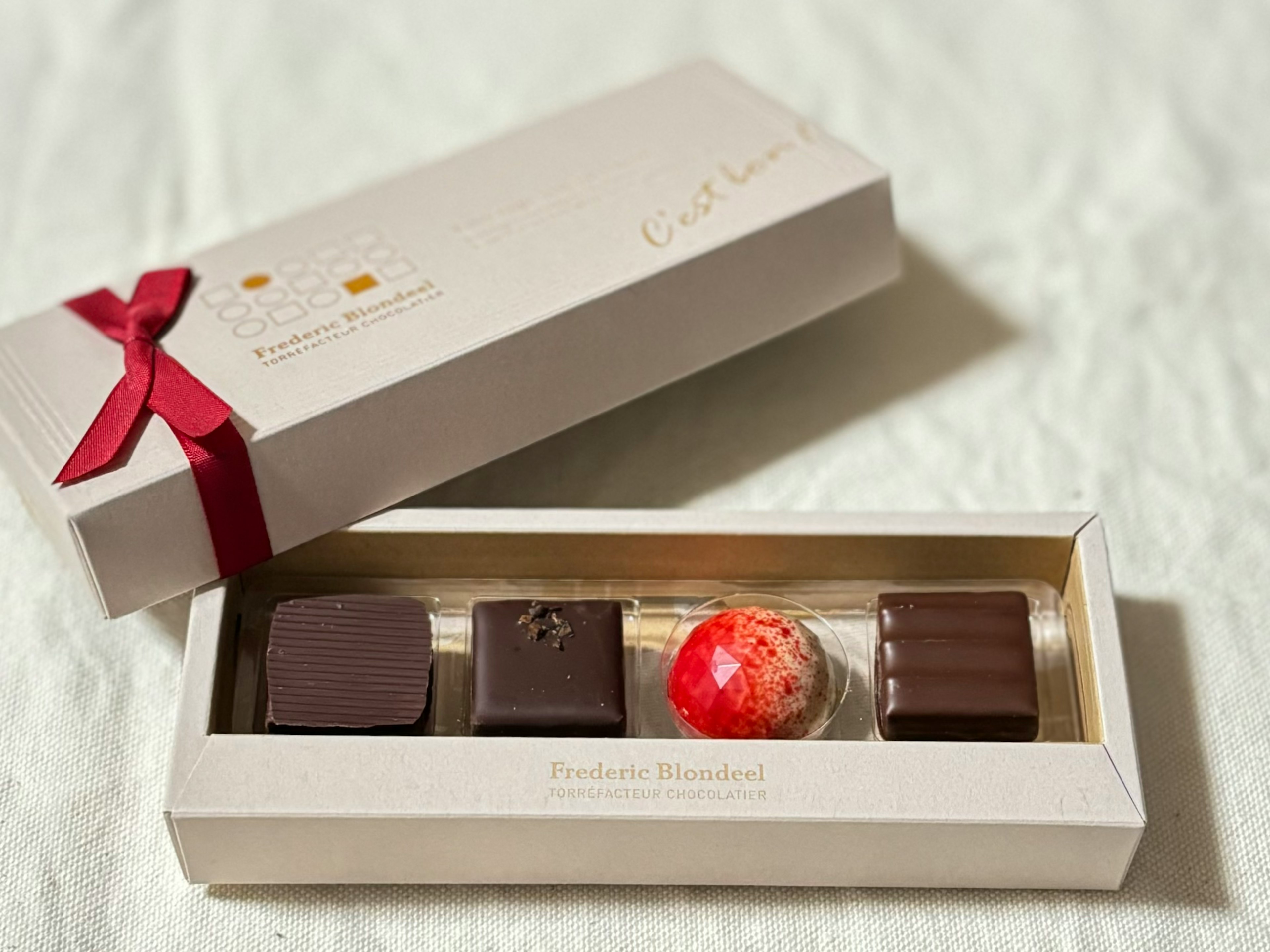 Boîte cadeau de chocolat élégante avec quatre chocolats exposés à l'intérieur dont une truffe colorée