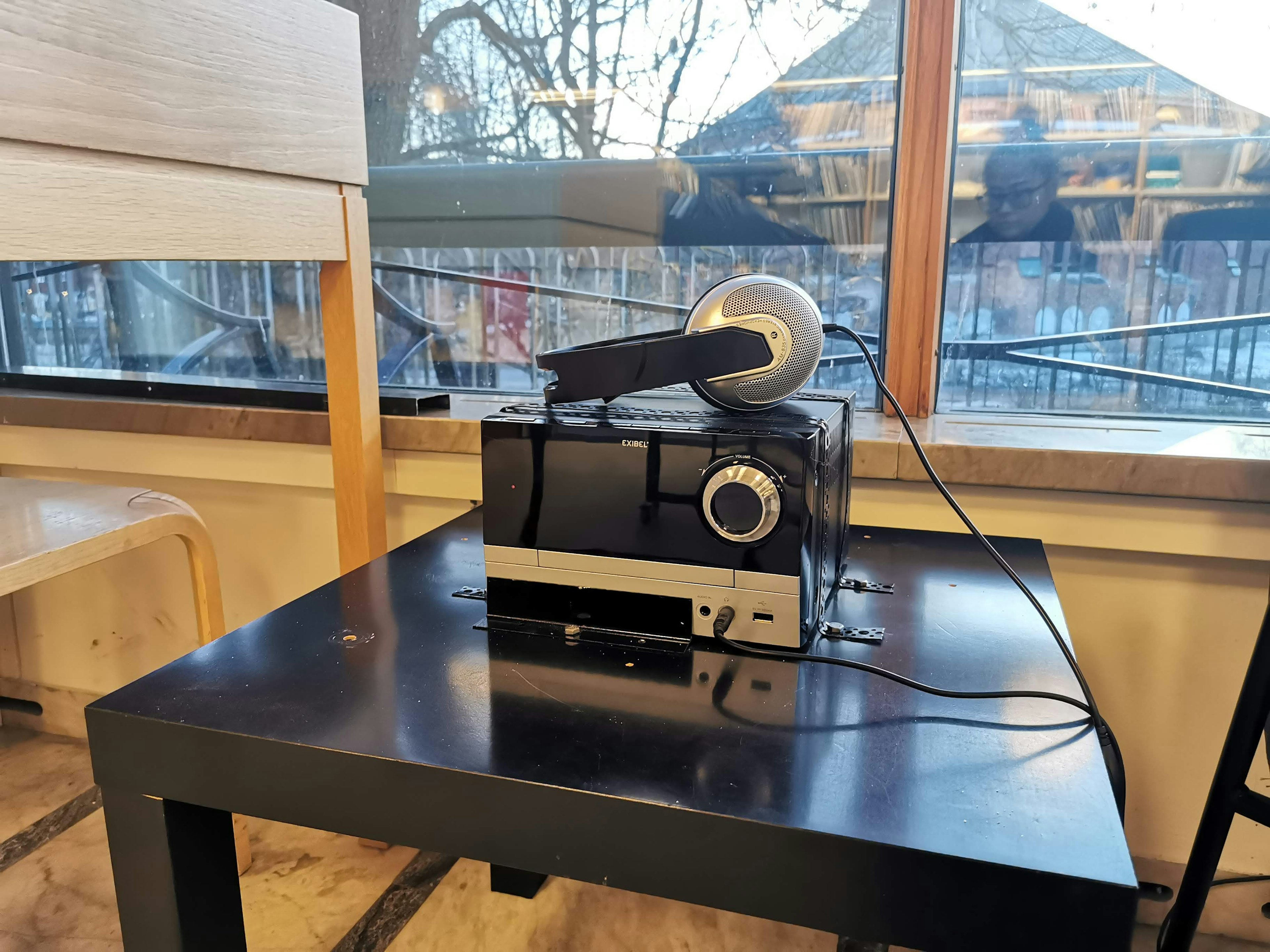 A projector and headphones placed on a table near a window with a view