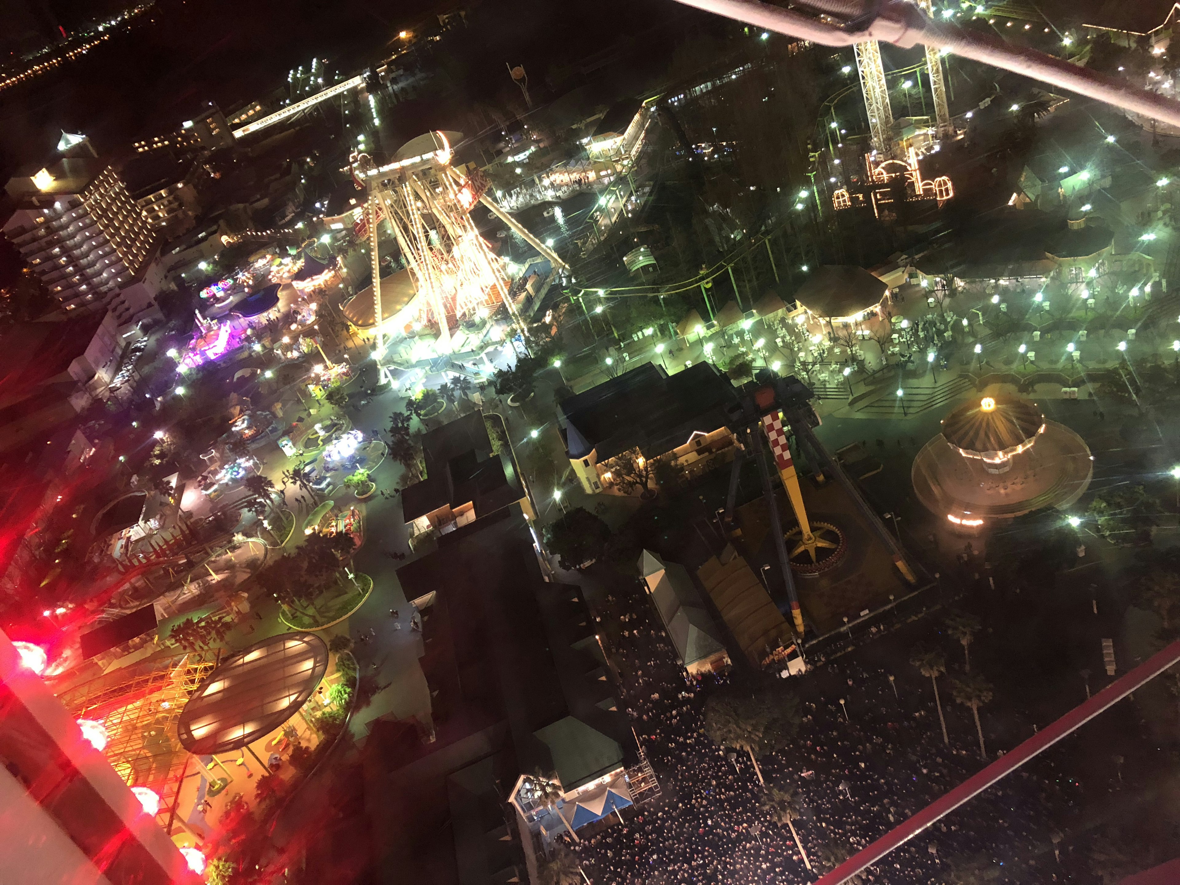 Vue aérienne d'un parc d'attractions la nuit avec plusieurs manèges et lumières vives