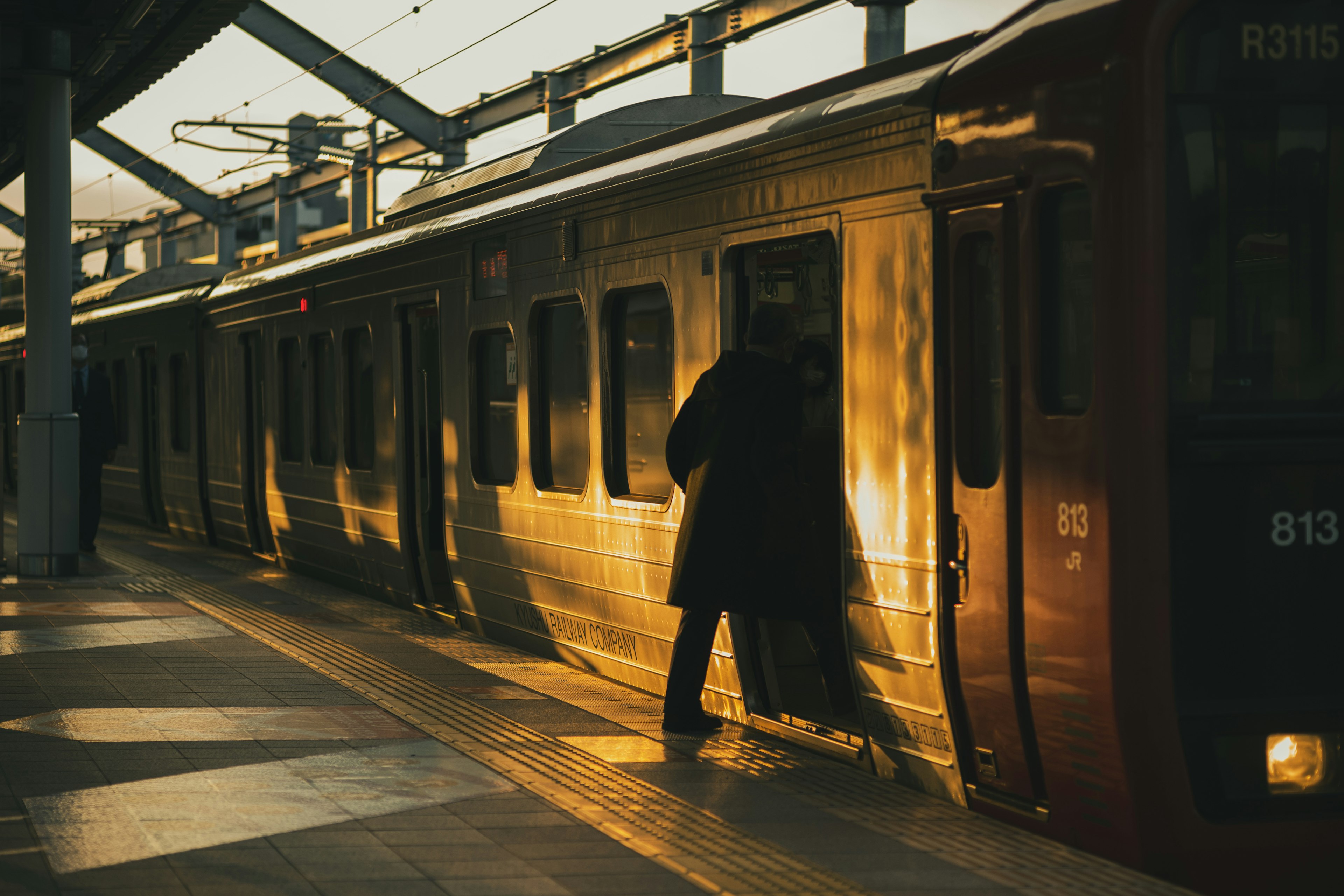 Una persona che sale su un treno al tramonto su una banchina di stazione