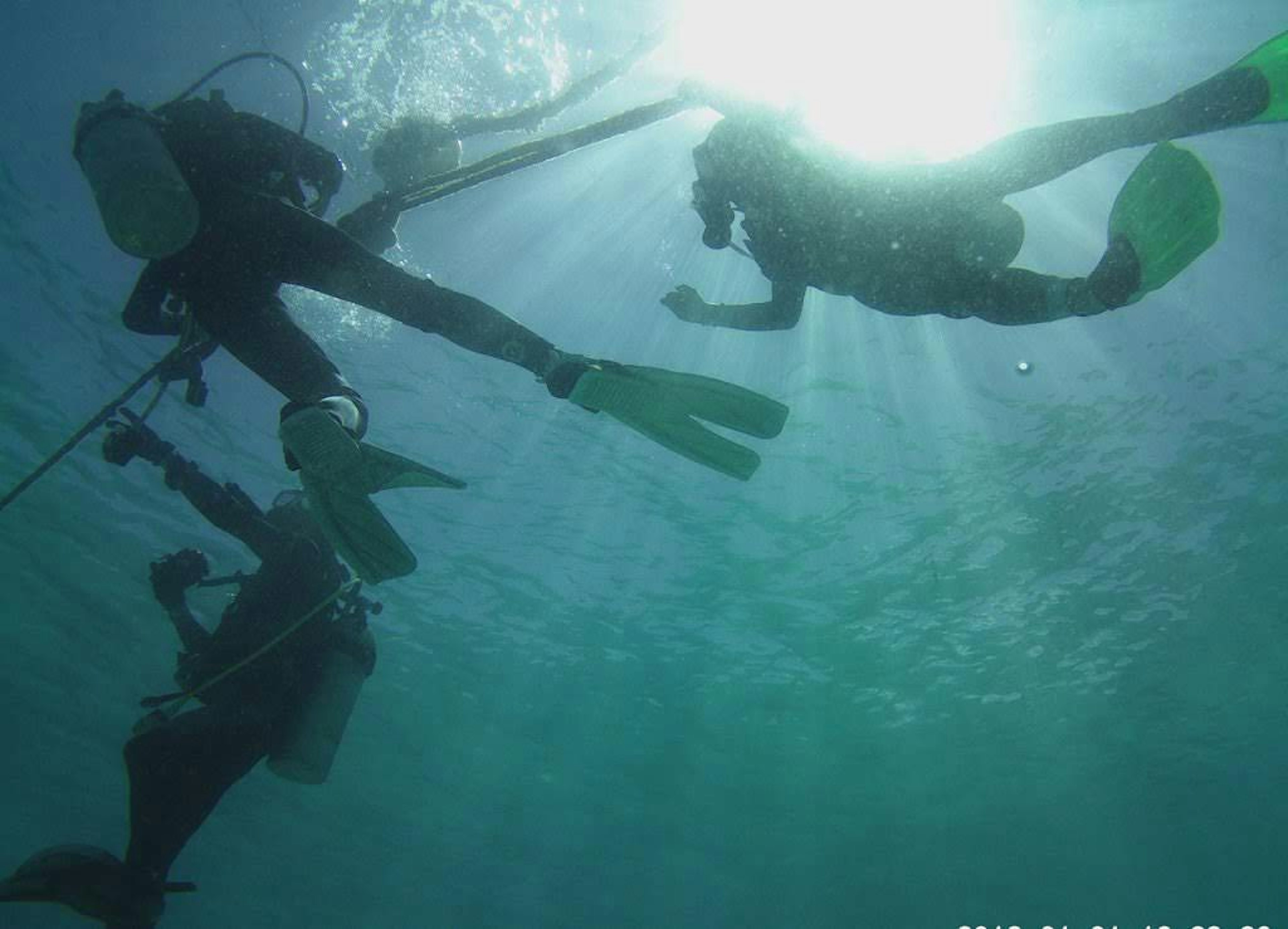 Silhouettes de plongeurs sous l'eau avec des reflets de lumière