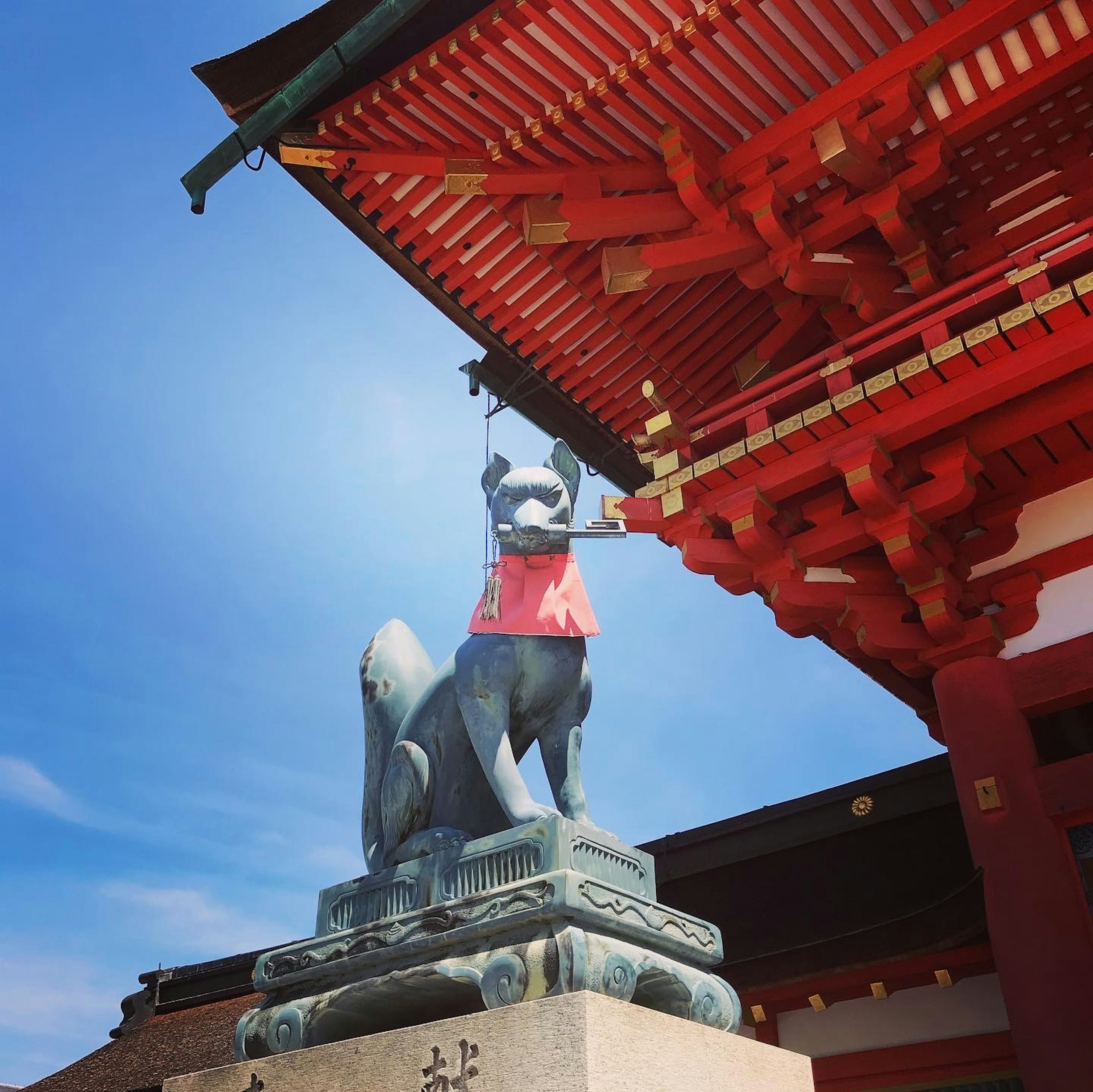 Statua di volpe con un mantello rosso sotto un tetto rosso