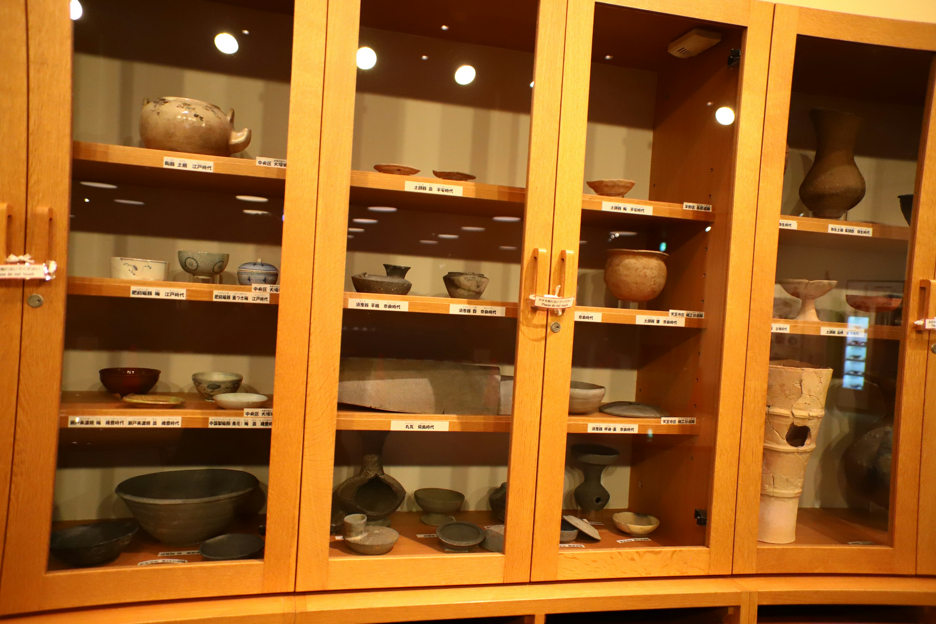 Collection of pottery displayed in a wooden showcase