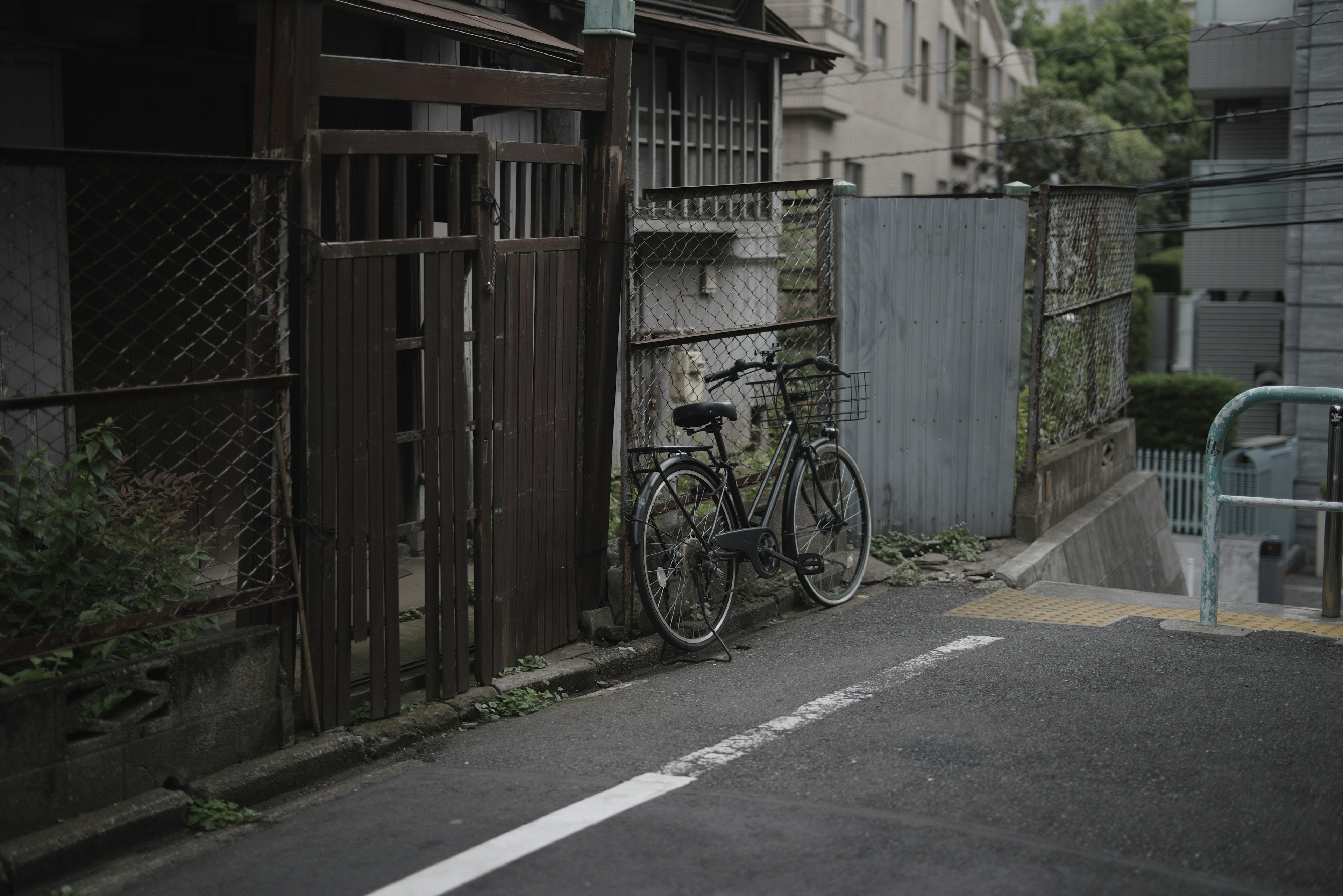 An old bicycle leaning against a fence in a narrow alley