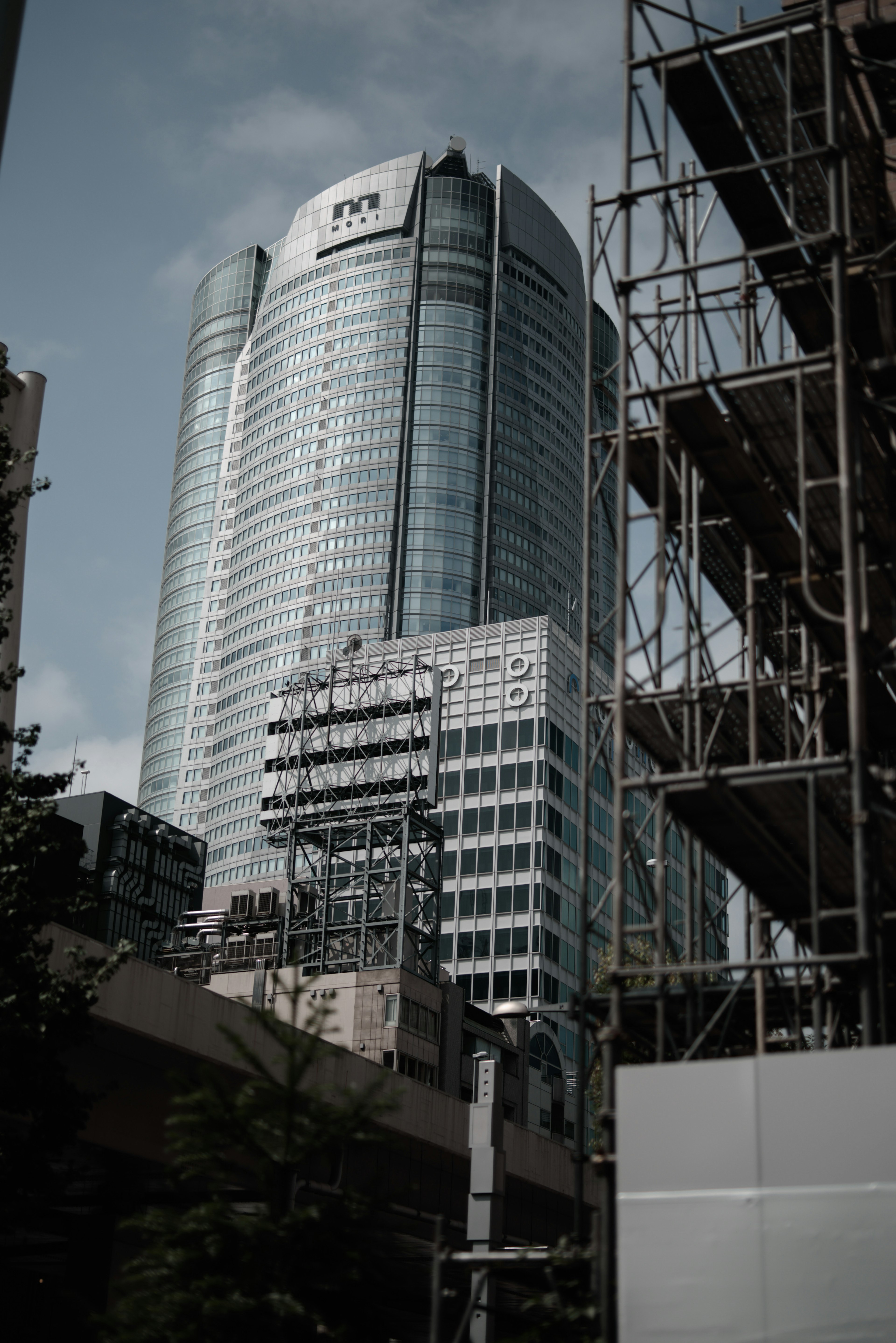 Gedung pencakar langit modern dengan fasad kaca dan lokasi konstruksi terdekat