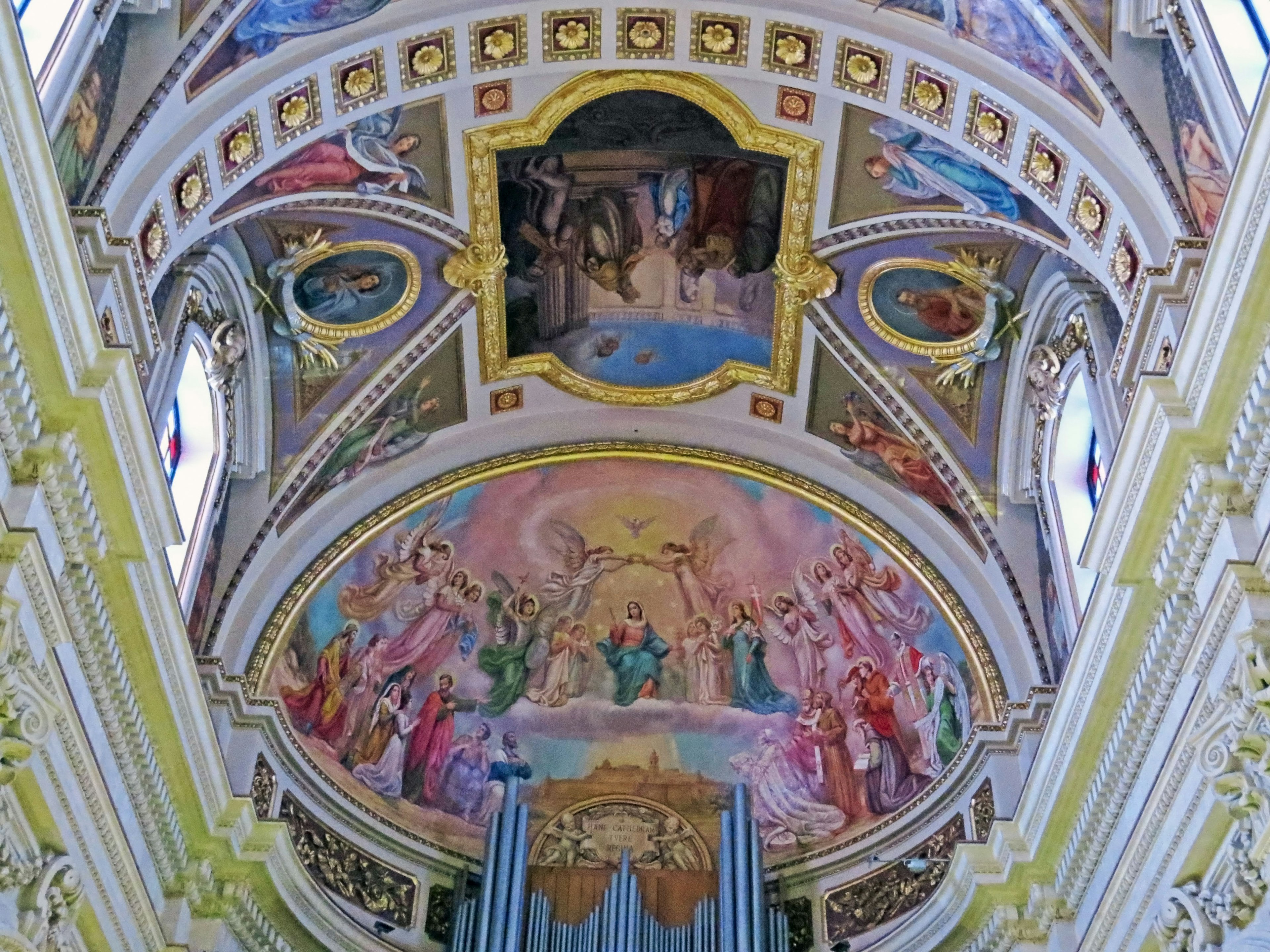 Interior of a church featuring a beautiful ceiling painting with vibrant murals and decorations