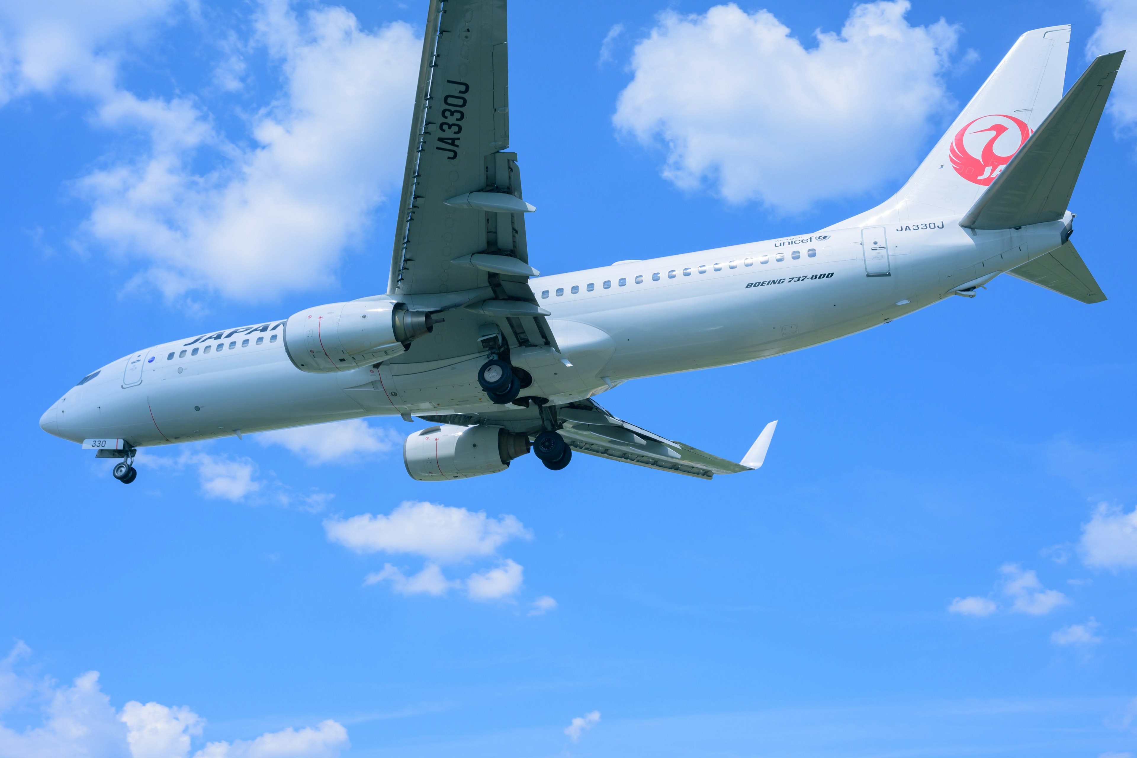 青空の下を飛行する白い航空機