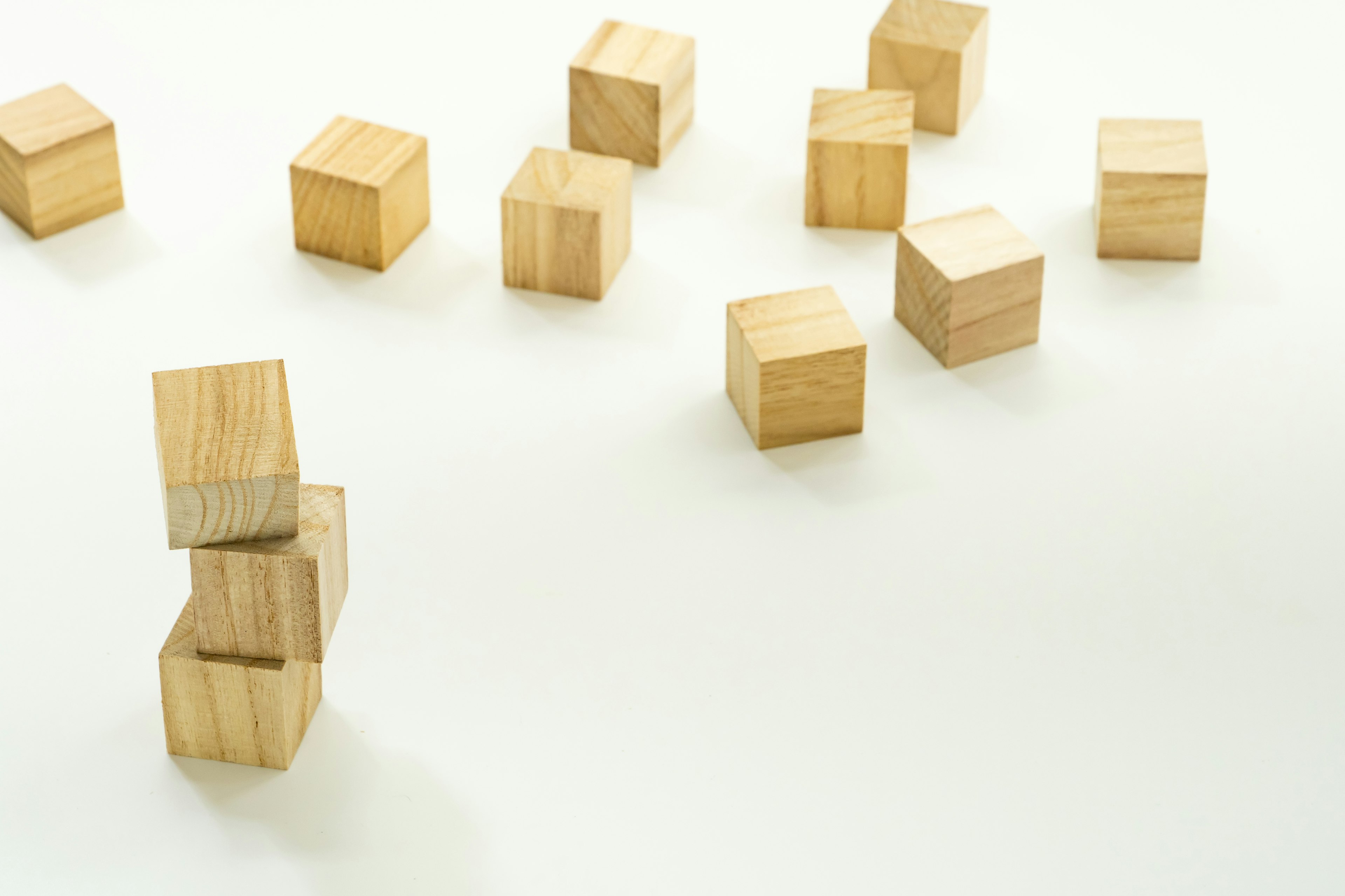 Scattered wooden cubes on a white background with one stack