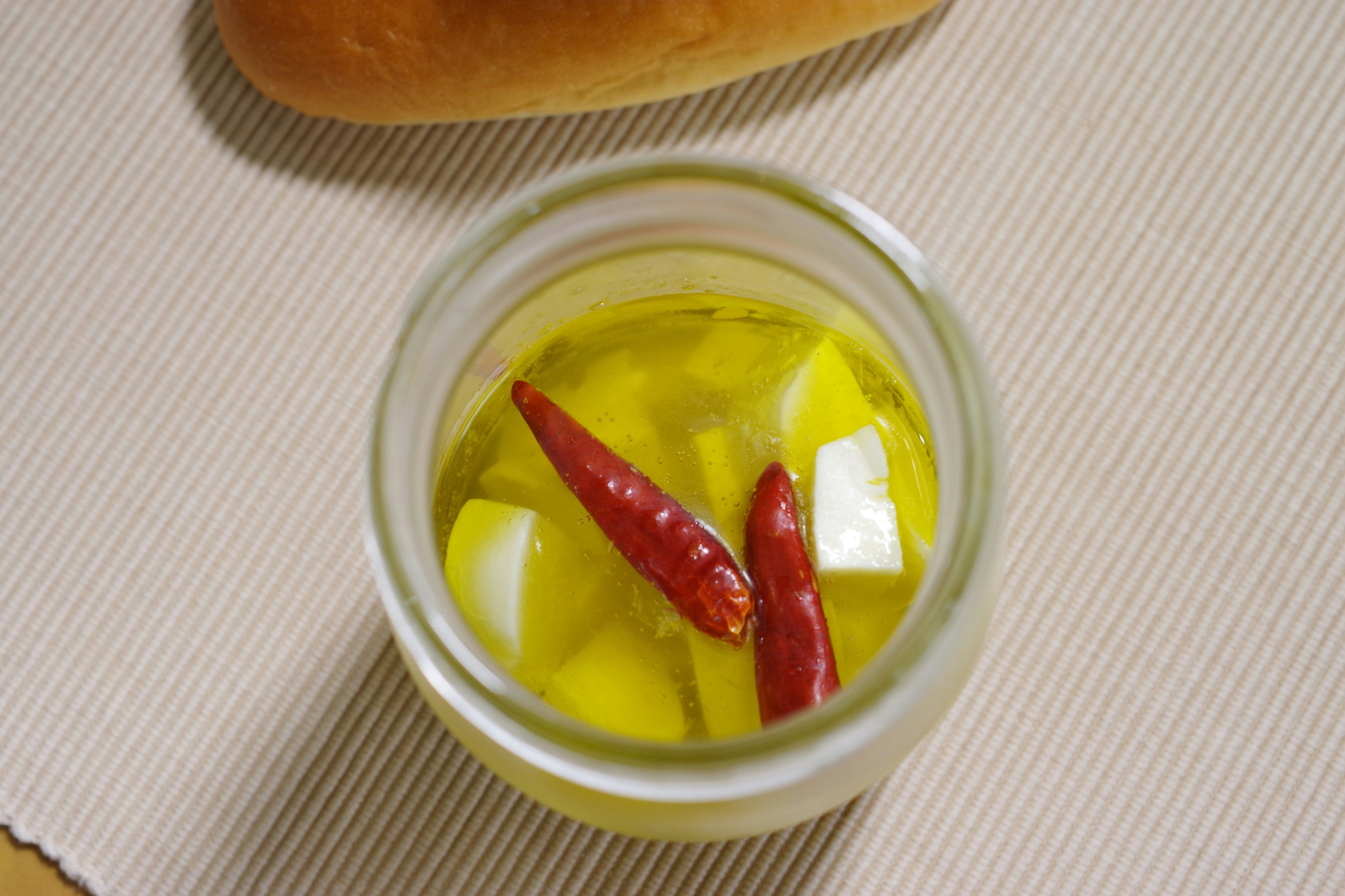 Jar of olive oil with red chili peppers and white garlic chunks