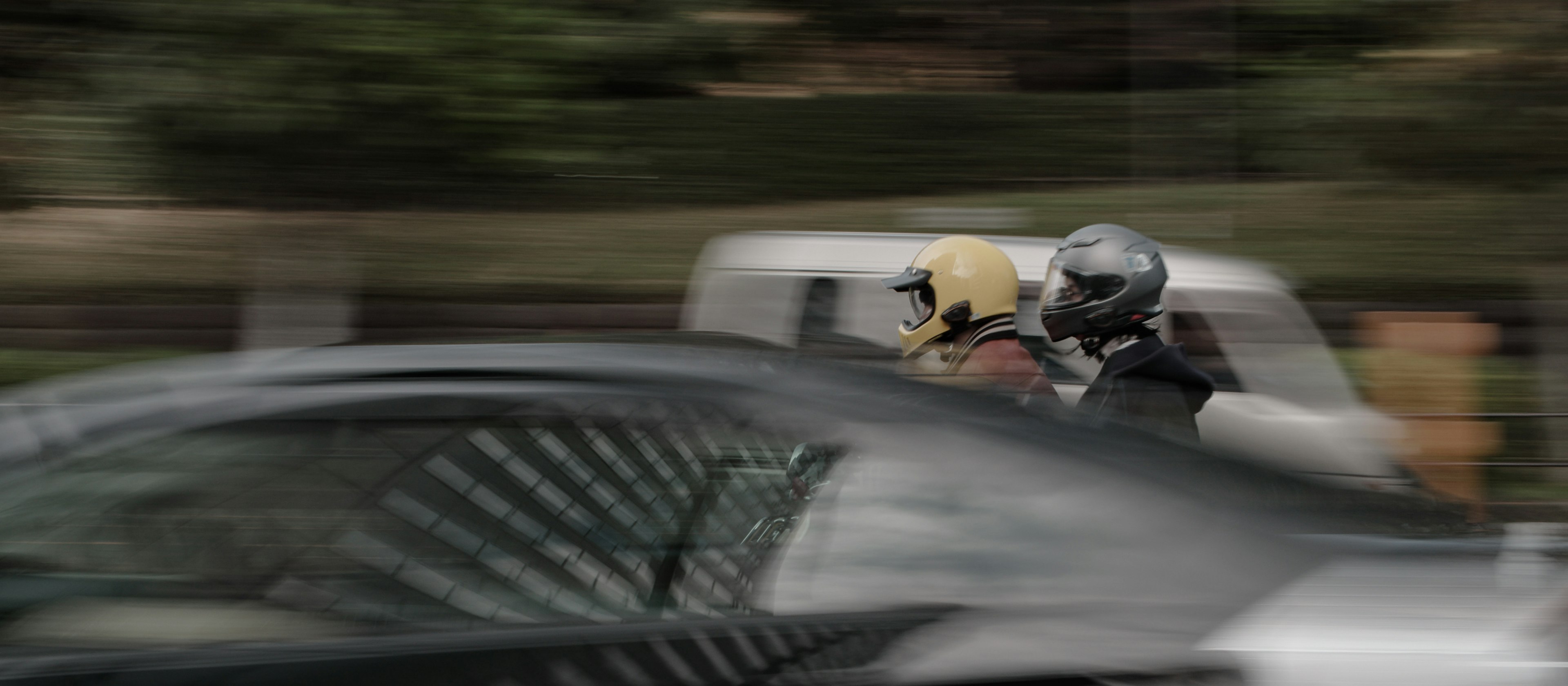 Zwei Personen auf einem Motorrad, die schnell vorbeifahren mit verschwommenen Autos um sie herum