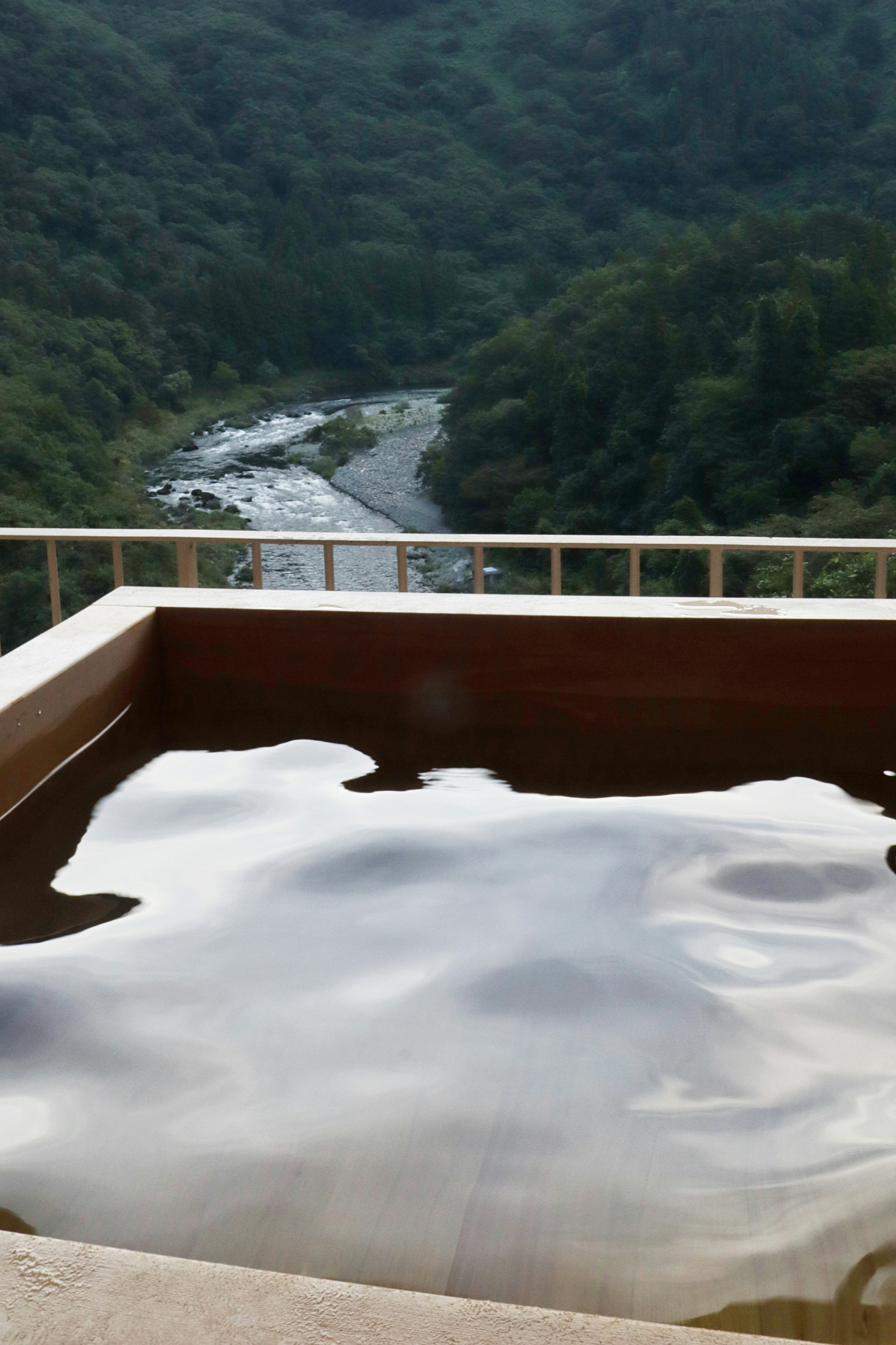 Pemandangan pemandian air panas yang indah menghadap sungai dan pegunungan