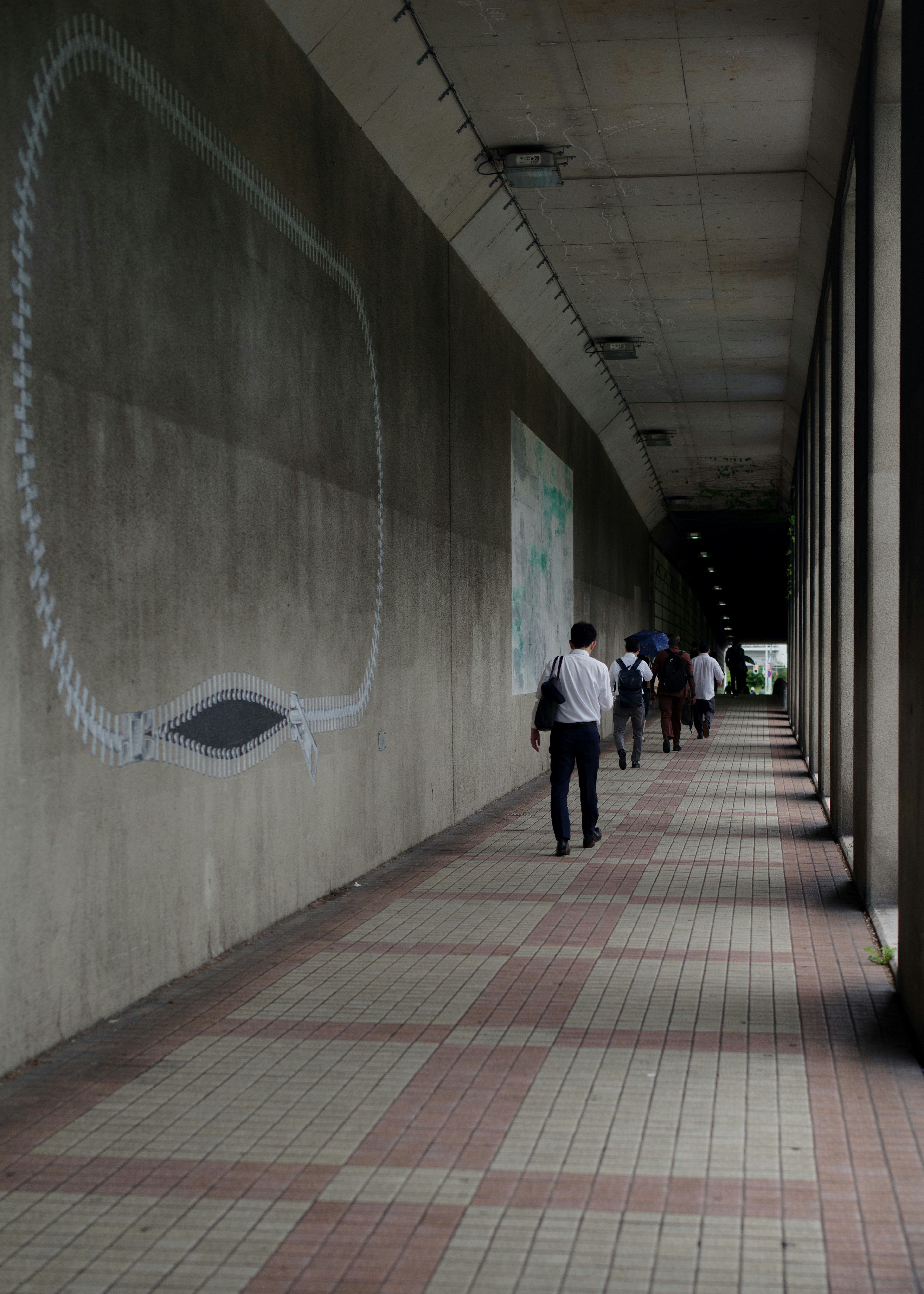 Des gens marchant le long d'un chemin en béton avec une œuvre d'art murale