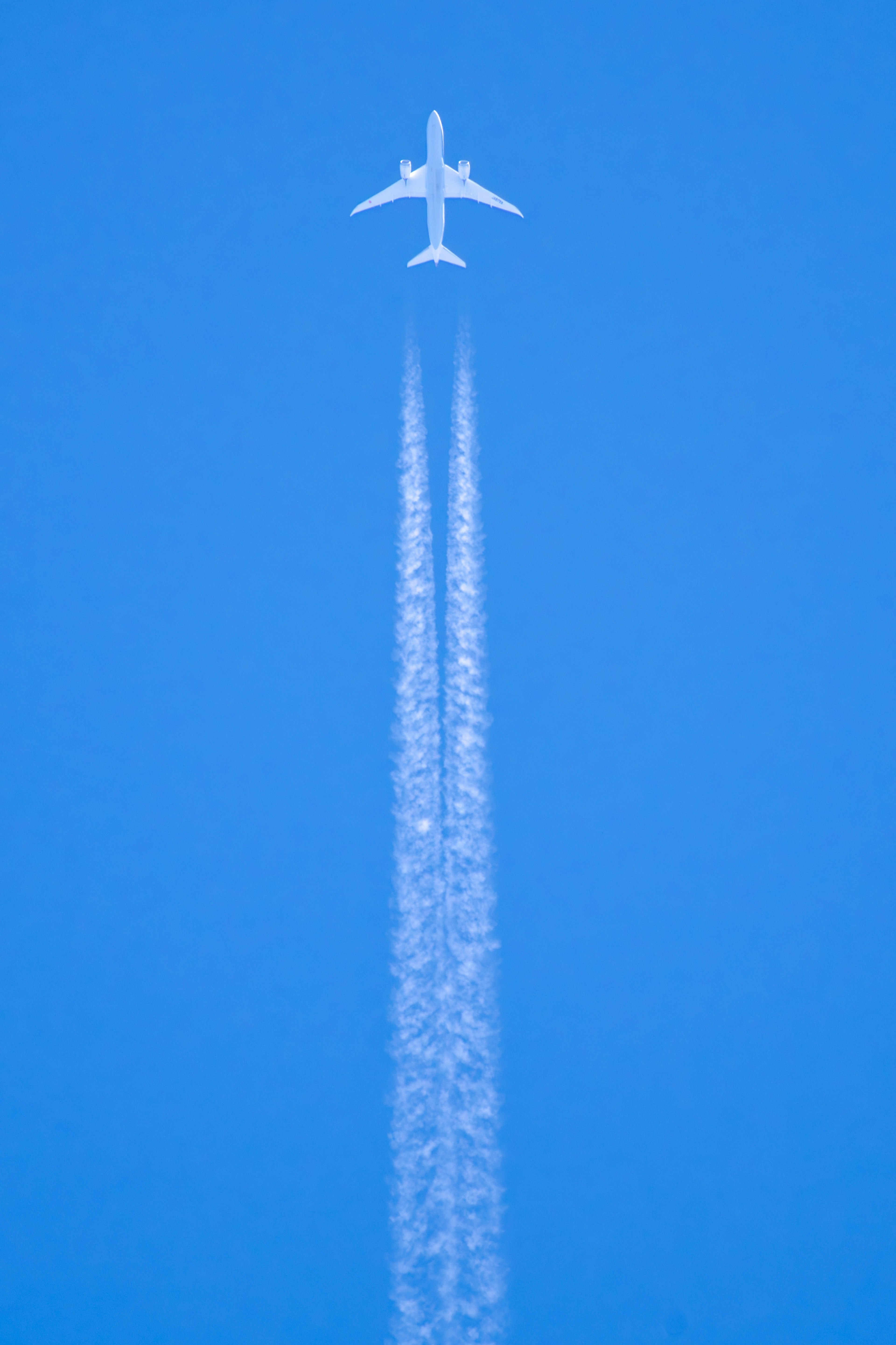 Flugzeug fliegt in einem blauen Himmel mit weißen Kondensstreifen