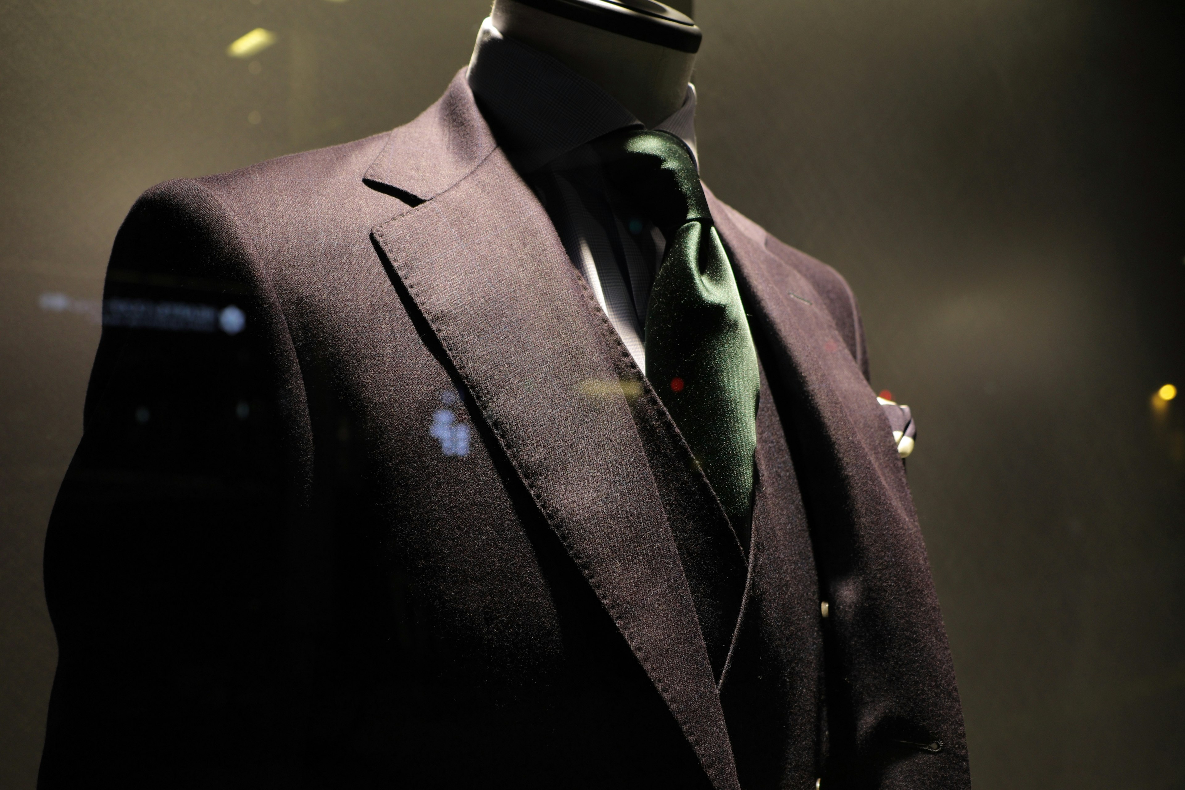 Elegant suit displayed in a dark setting with a green tie