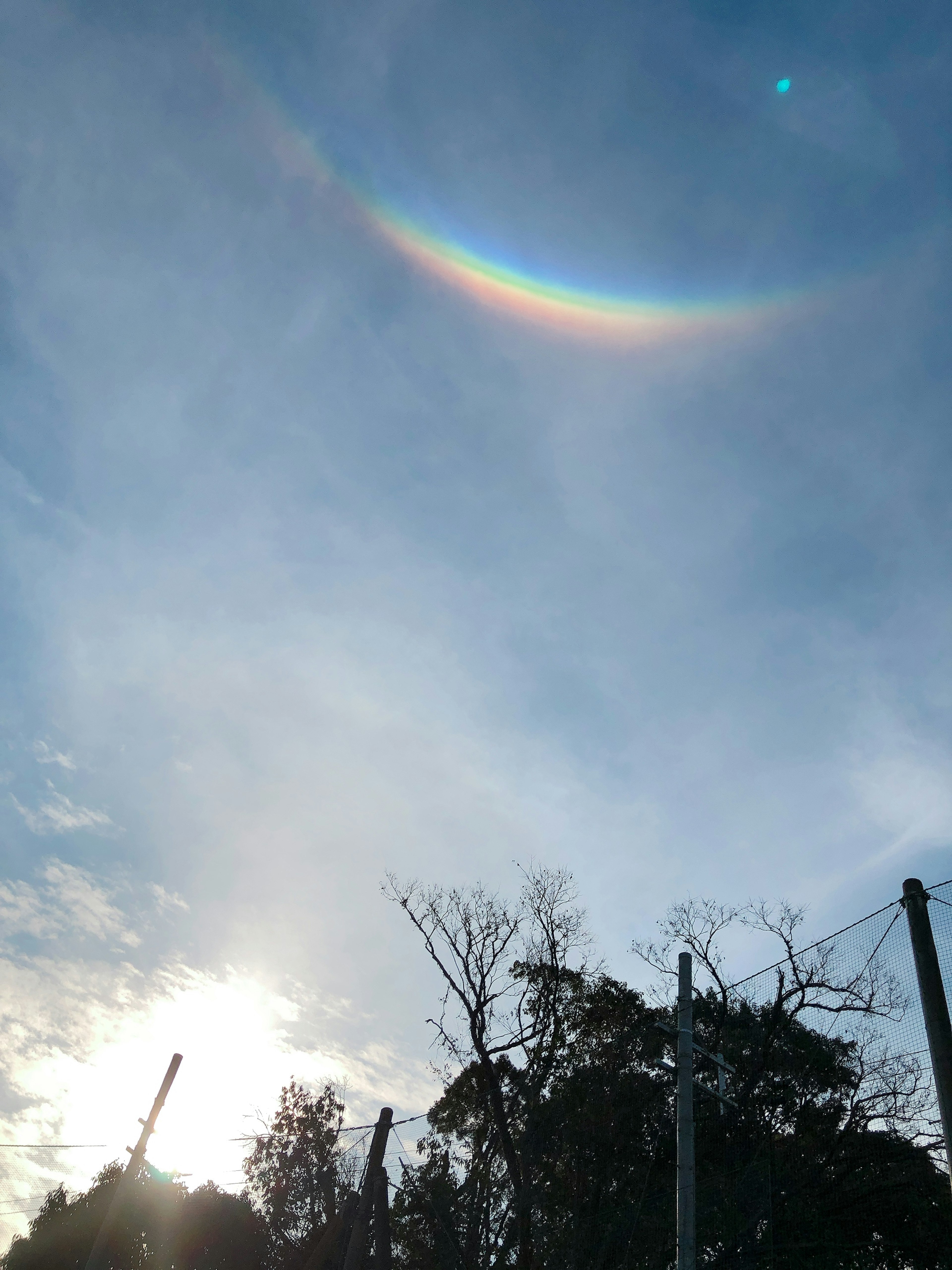 Un paisaje con un arco colorido que se asemeja a un arcoíris en el cielo azul