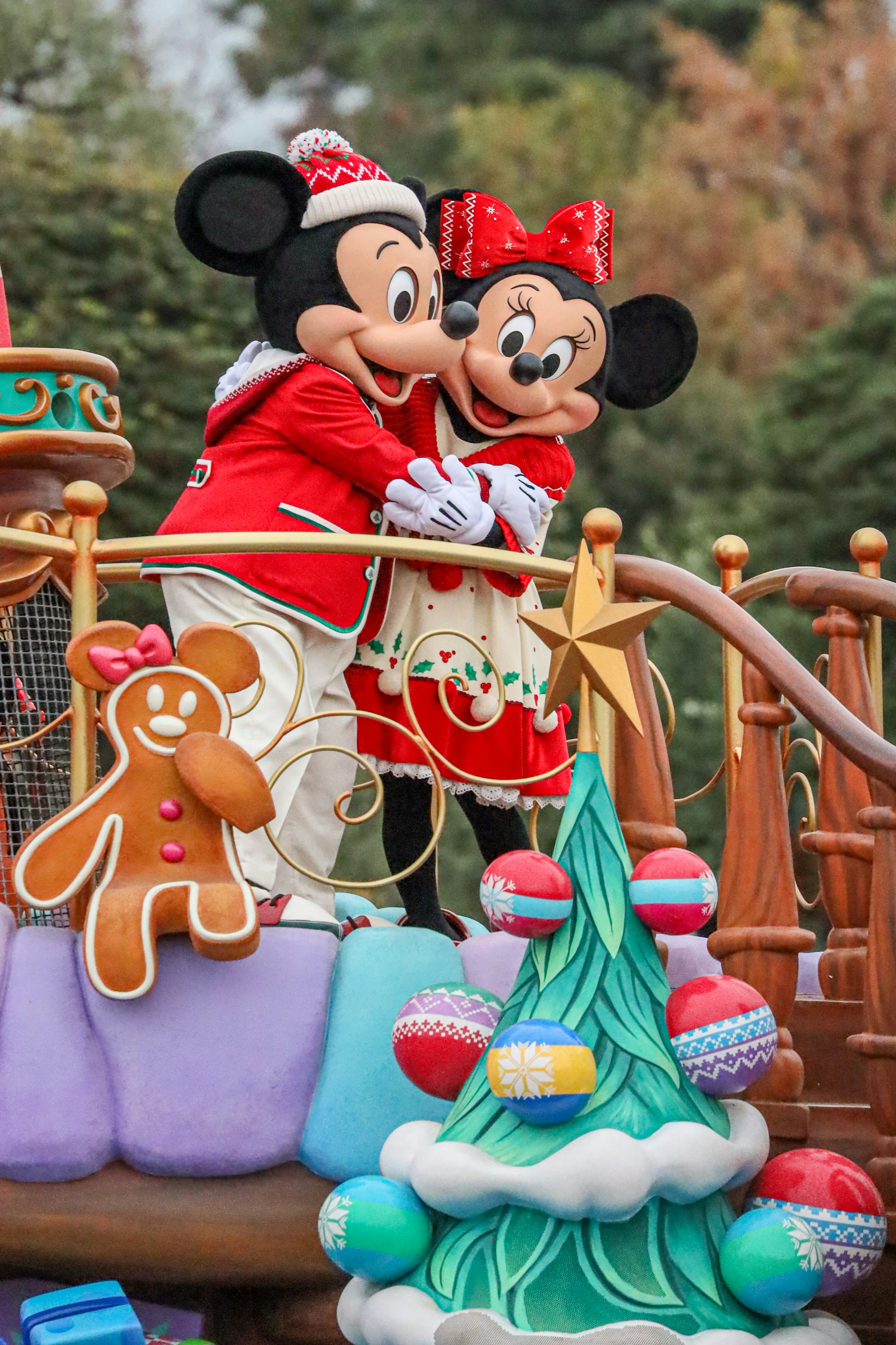 Mickey Mouse and Minnie Mouse dressed in Christmas outfits embracing in a festive setting