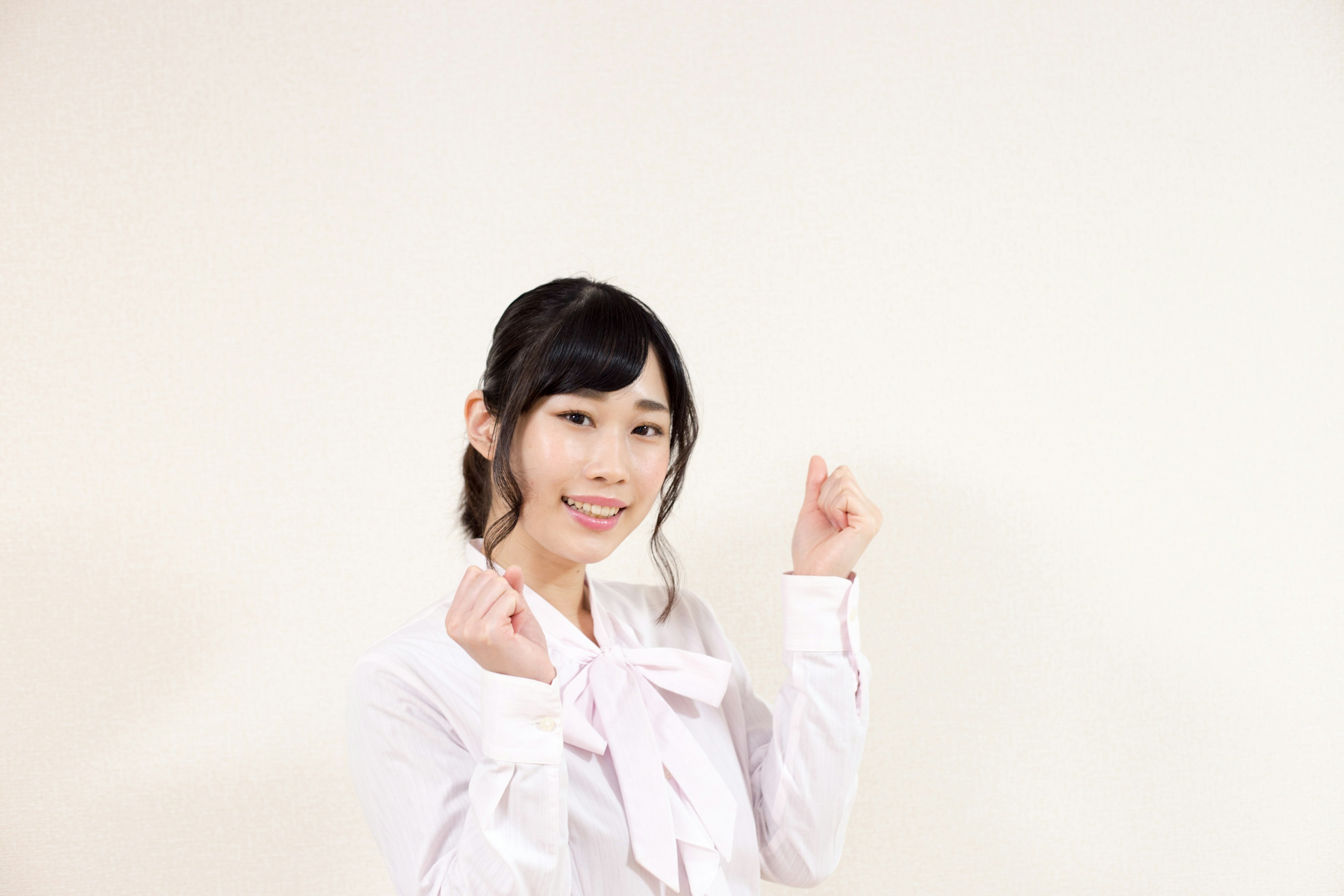 Woman smiling and raising her hands in front of a white background