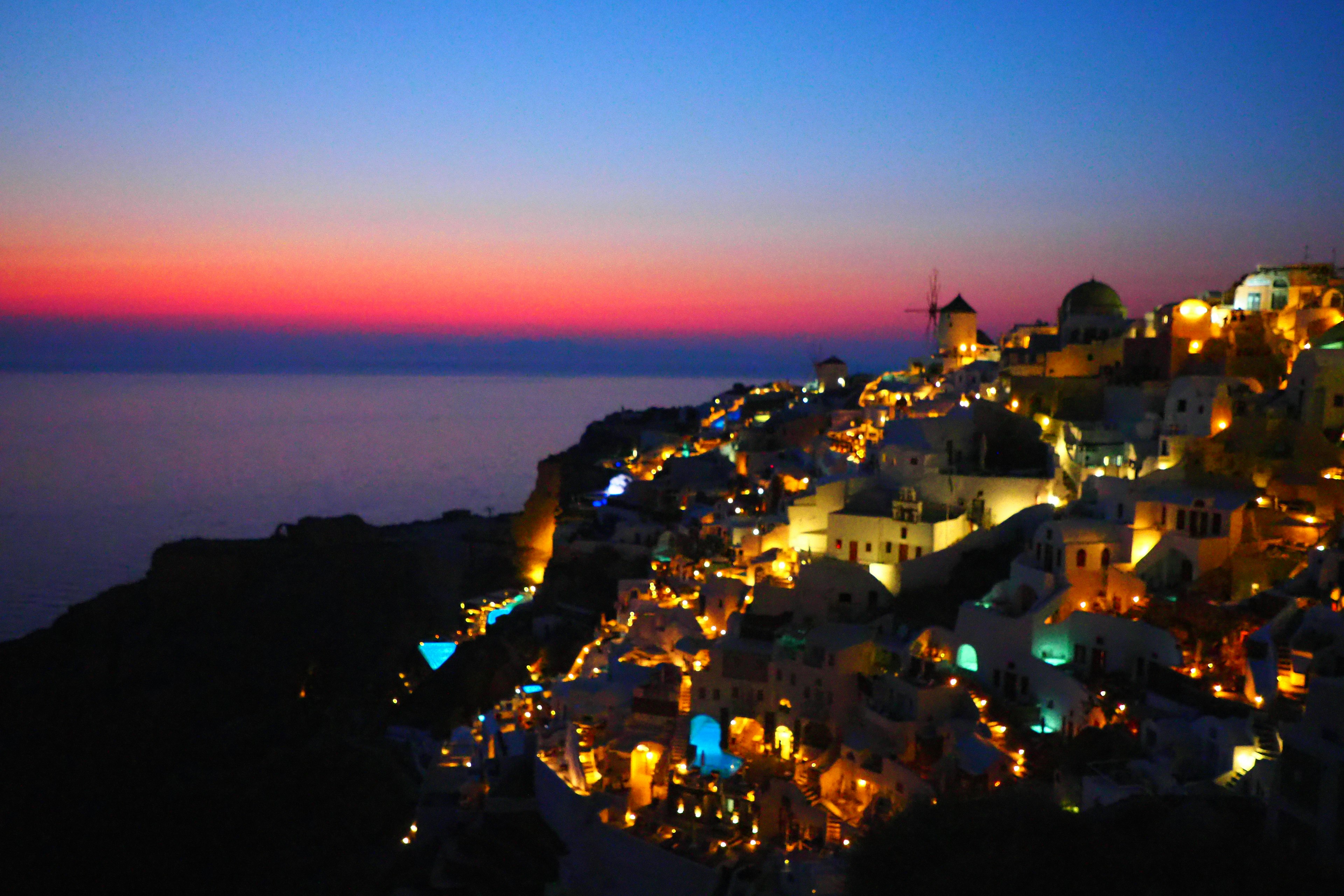 Pemandangan matahari terbenam yang indah di pulau Santorini dengan rumah-rumah yang diterangi