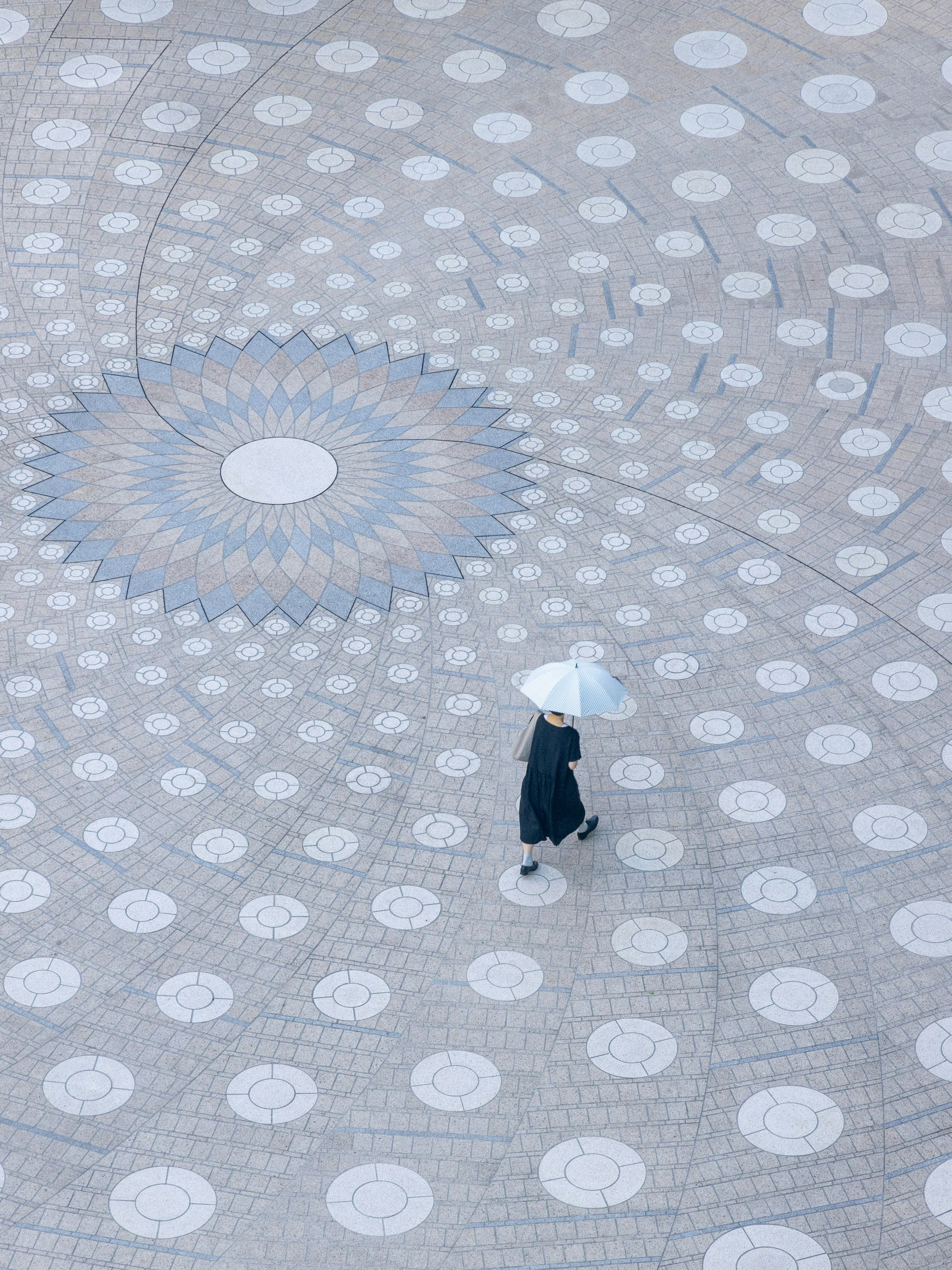 Une femme tenant un parapluie marchant sur une surface carrelée avec des motifs bleus