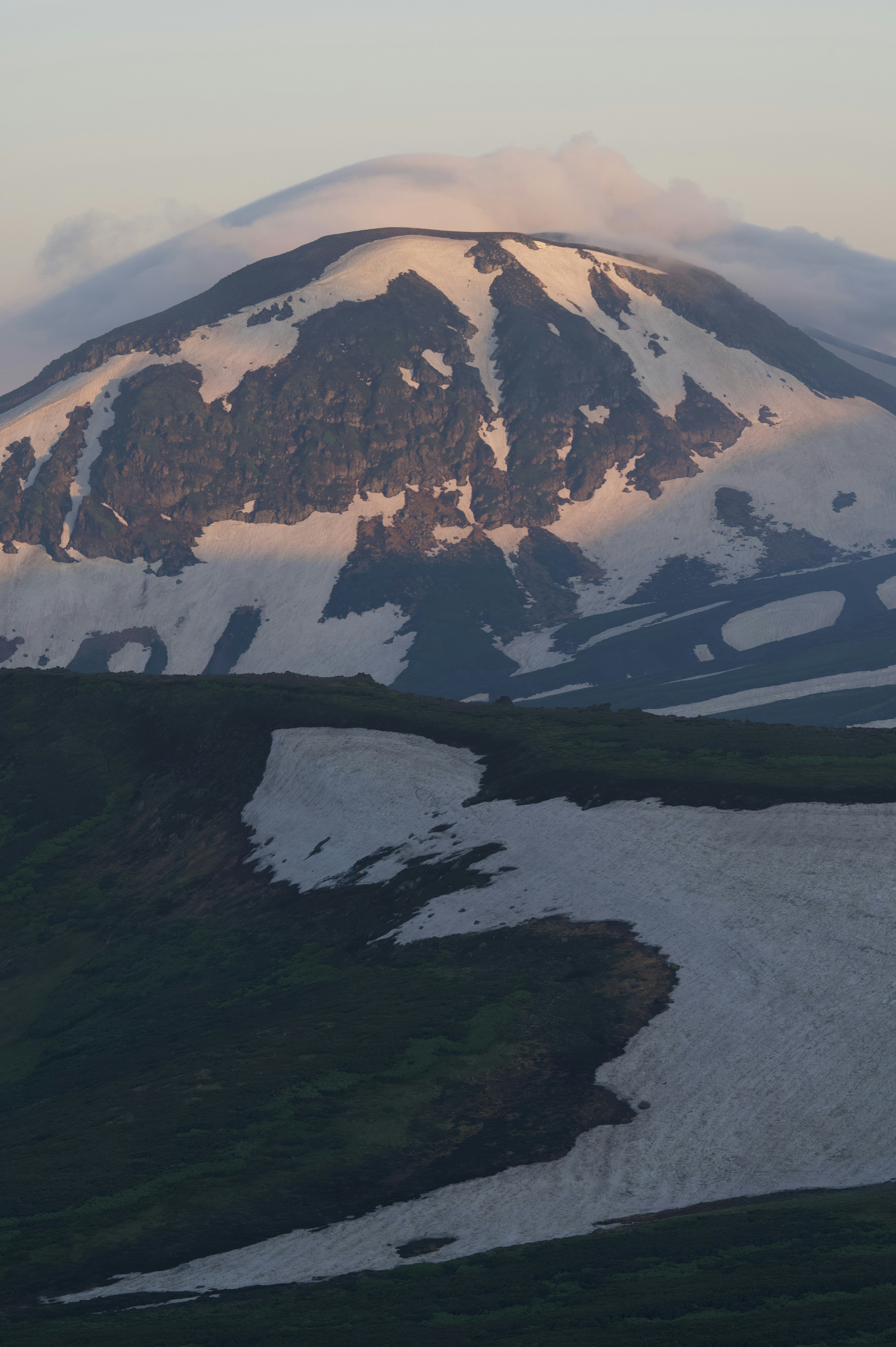 Snow-covered mountain landscape with green hills