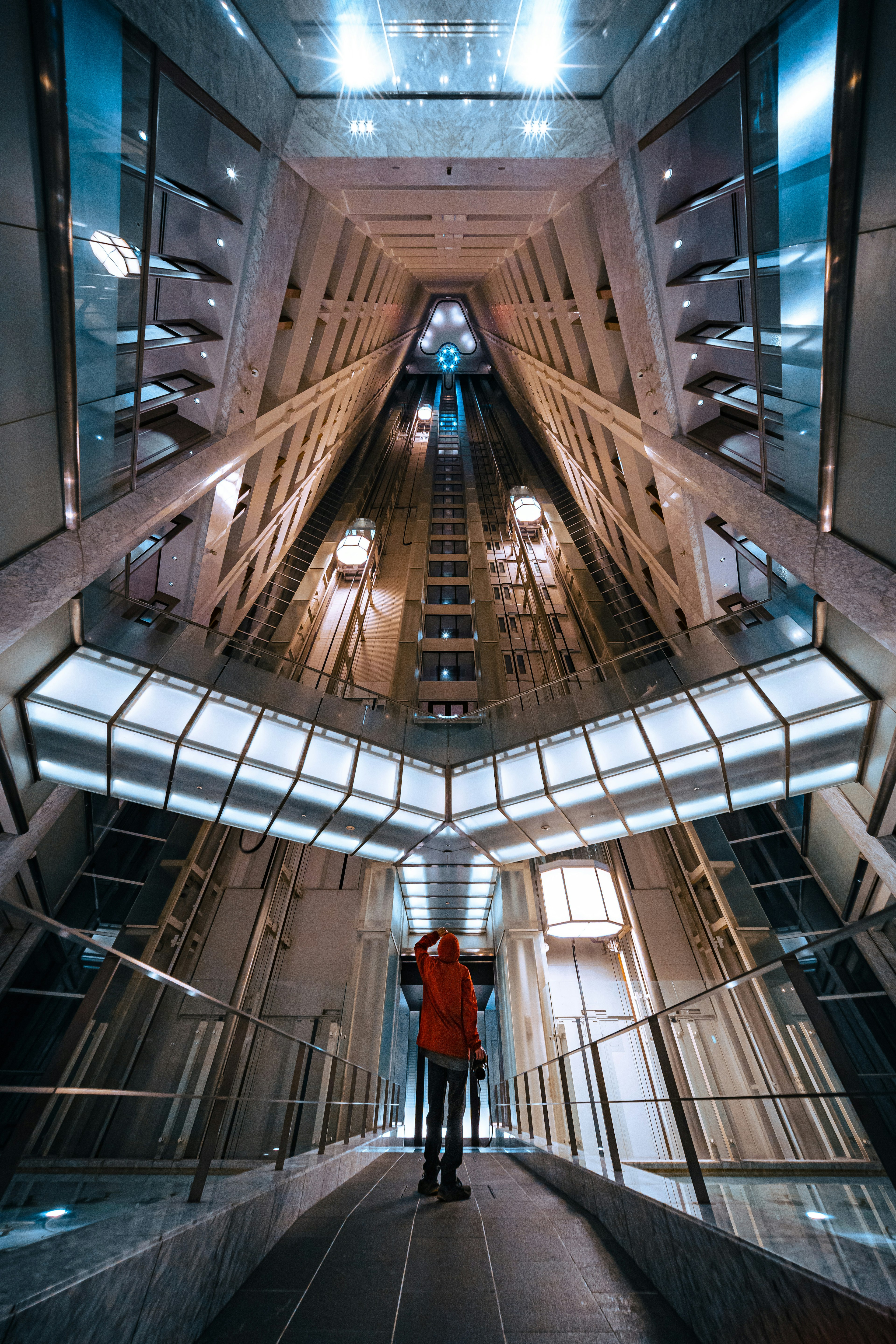 Seseorang berdiri di dalam shaft lift futuristik dengan arsitektur geometris