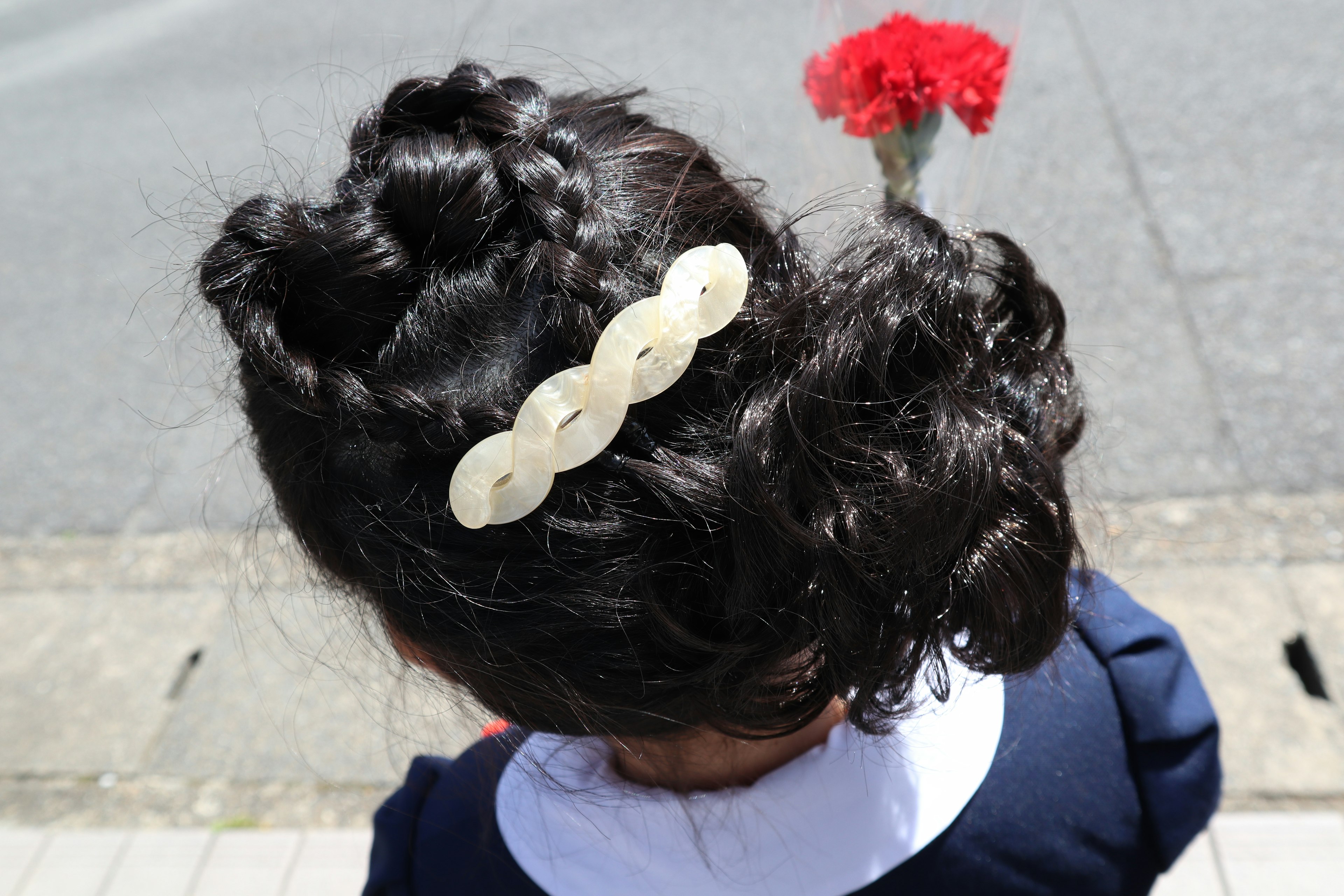 黒い巻き髪に白いヘアアクセサリーをつけた子供の後頭部